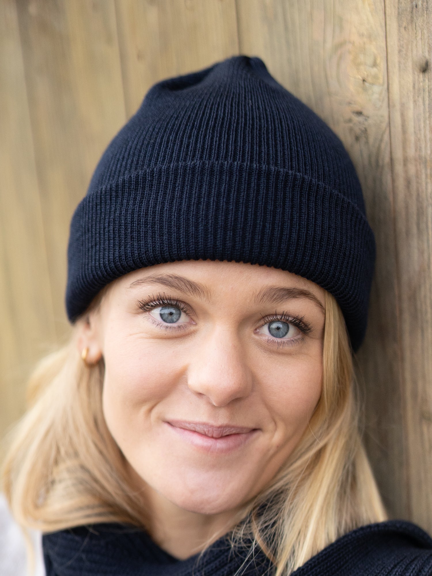Nachhaltige FUXBAU Fair Fashion Merino Strickmütze in Navy aus 100% GOTS zertifizierter Merino Schurwolle. Nachhaltig gestrickt in Deutschland und getragen von einer jungen blonden Frau.