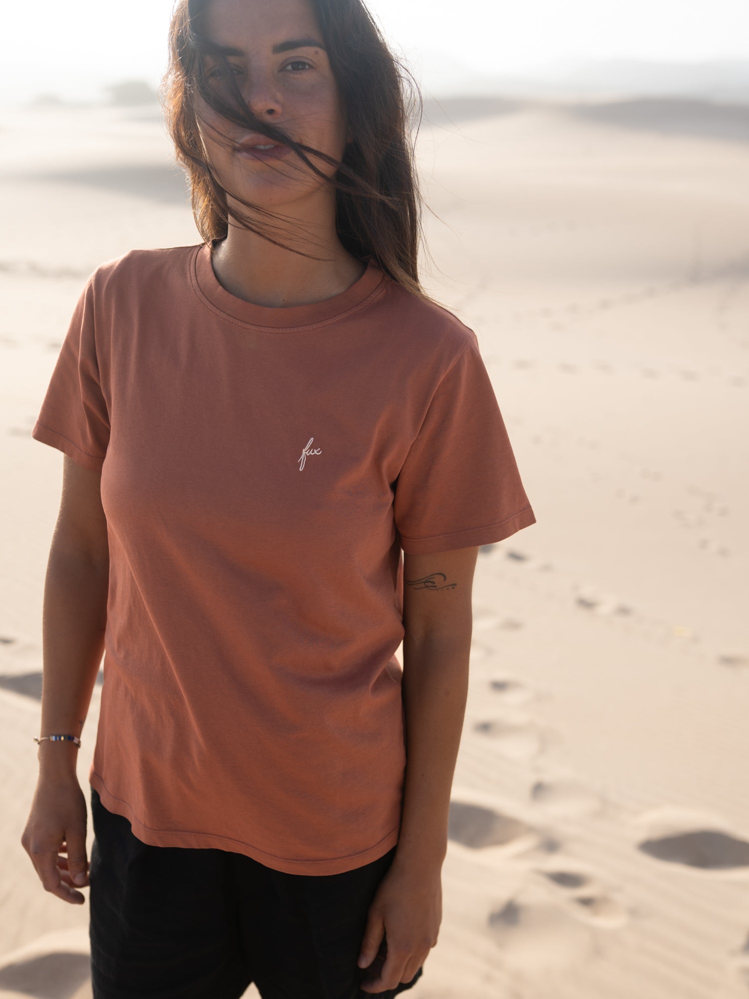 Frau trägt rotes FUXBAU T-Shirt aus Biobaumwolle in den Dünen