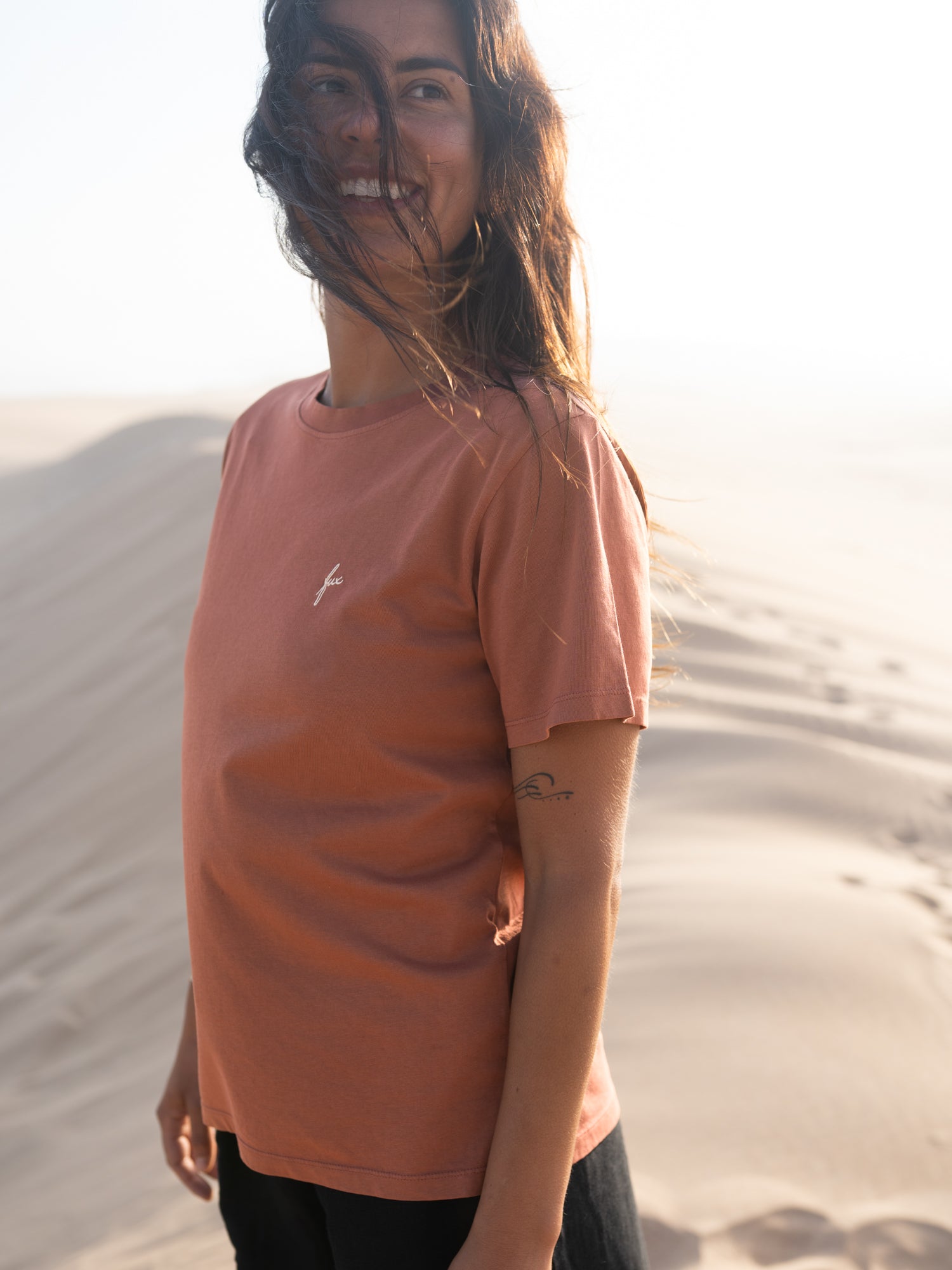Frau trägt fair gefertigtes rotes FUXBAU T-Shirt aus Biobaumwolle bei warmem Abendlicht