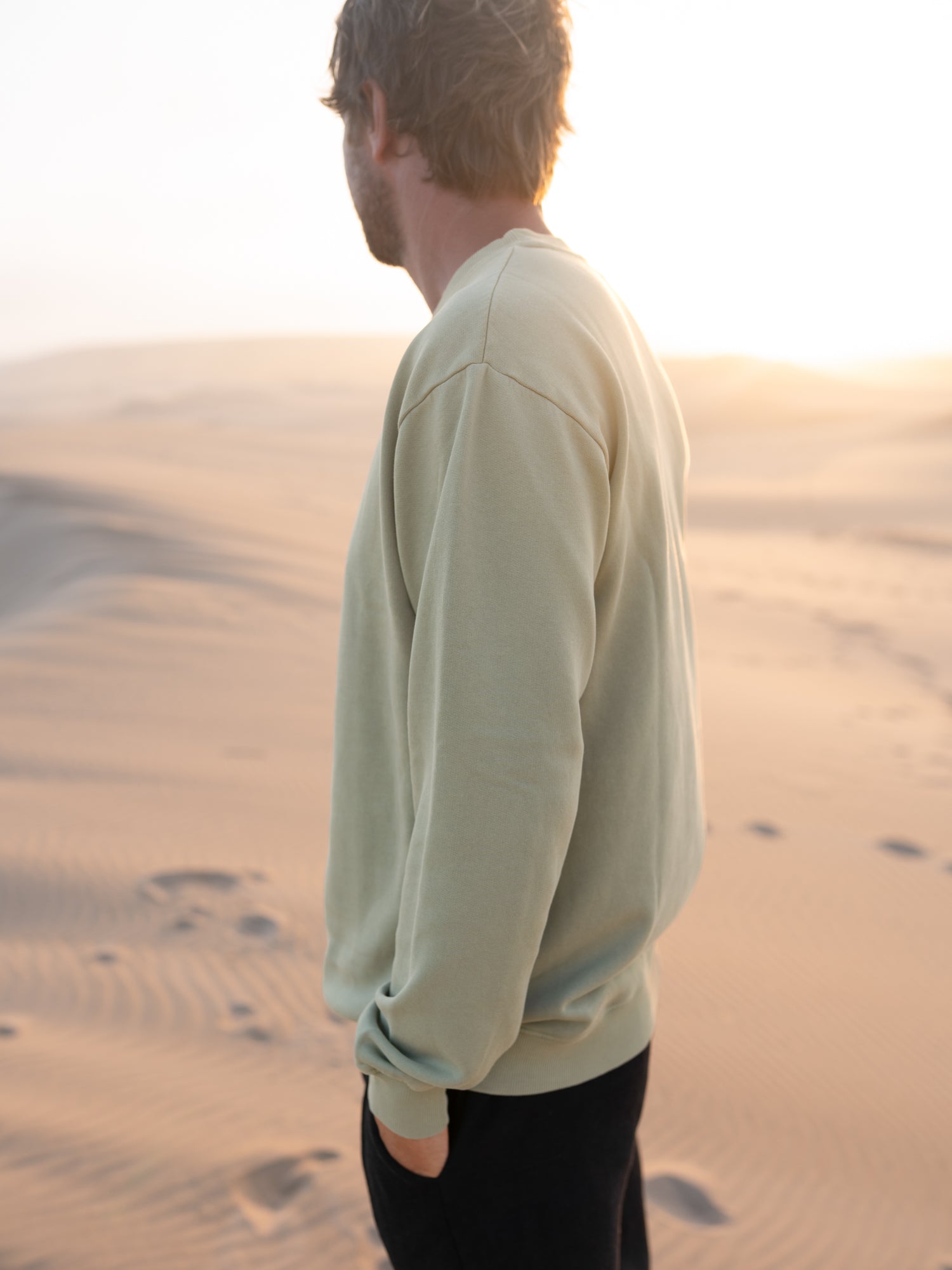 Seegrüner Männer Pullover von FUXBAU im Vintage Look vor heller Dünenlandschaft