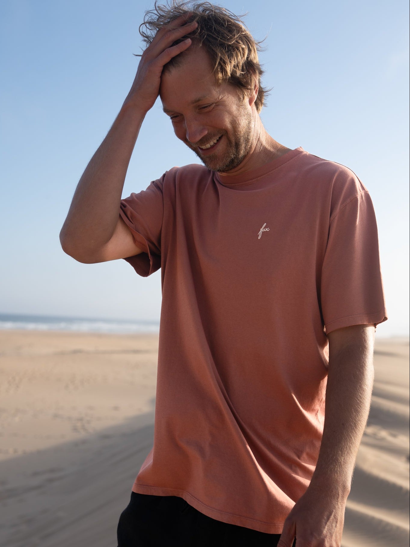 Stückgefärbtes rotes Männer T-Shirt von FUXBAU mit dezentem Stick am Strand