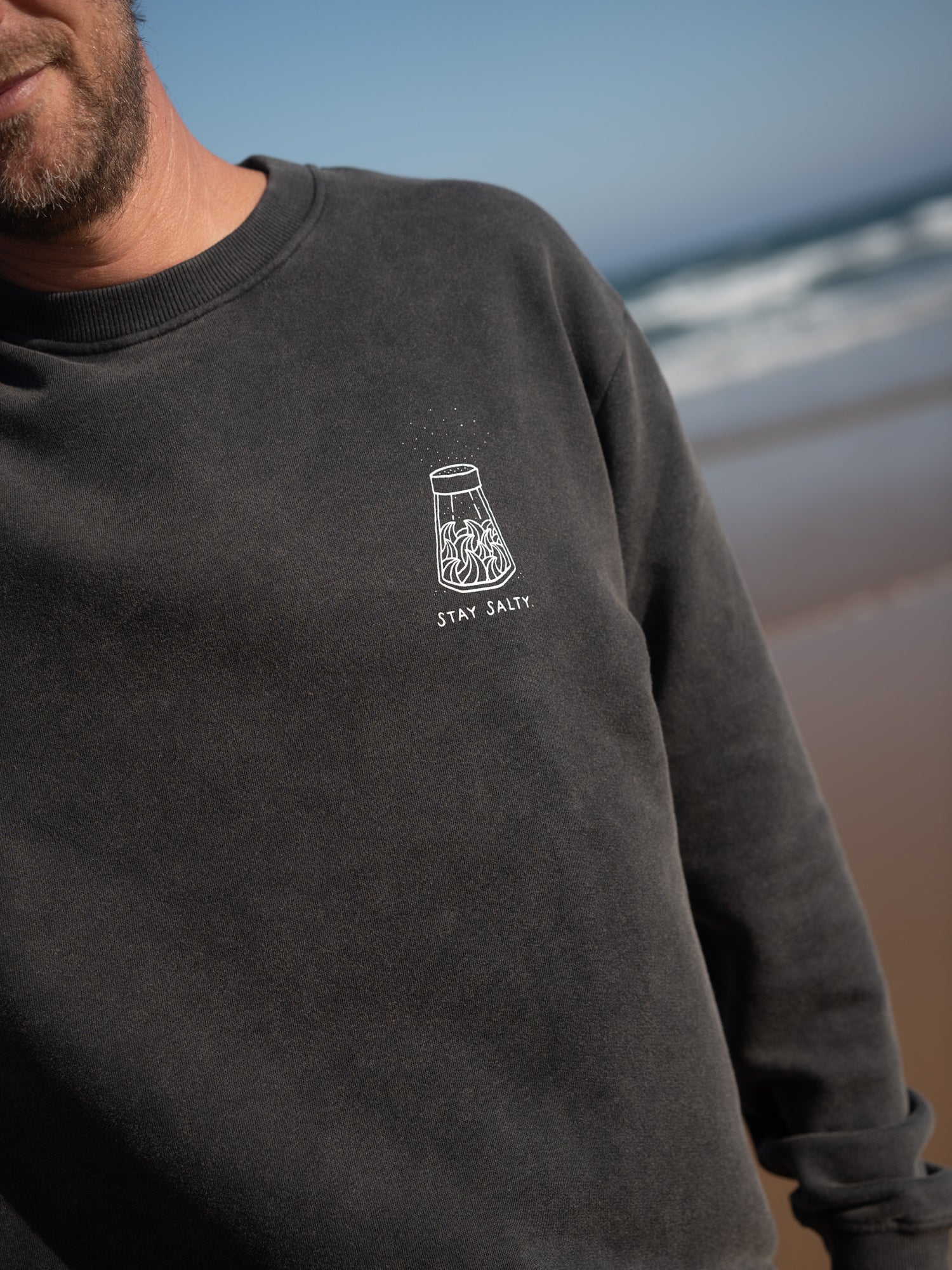 Detail des Stay Salty Prints auf salzschwarzem Sweater