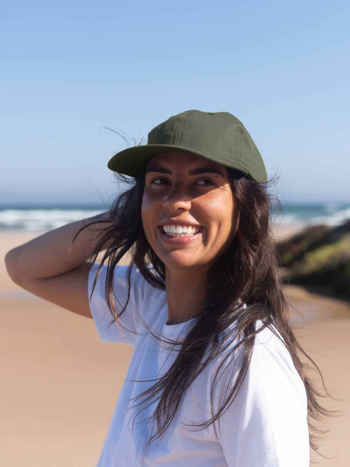 Frau trägt olivgrüne Dad Cap aus Biobaumwolle am Strand