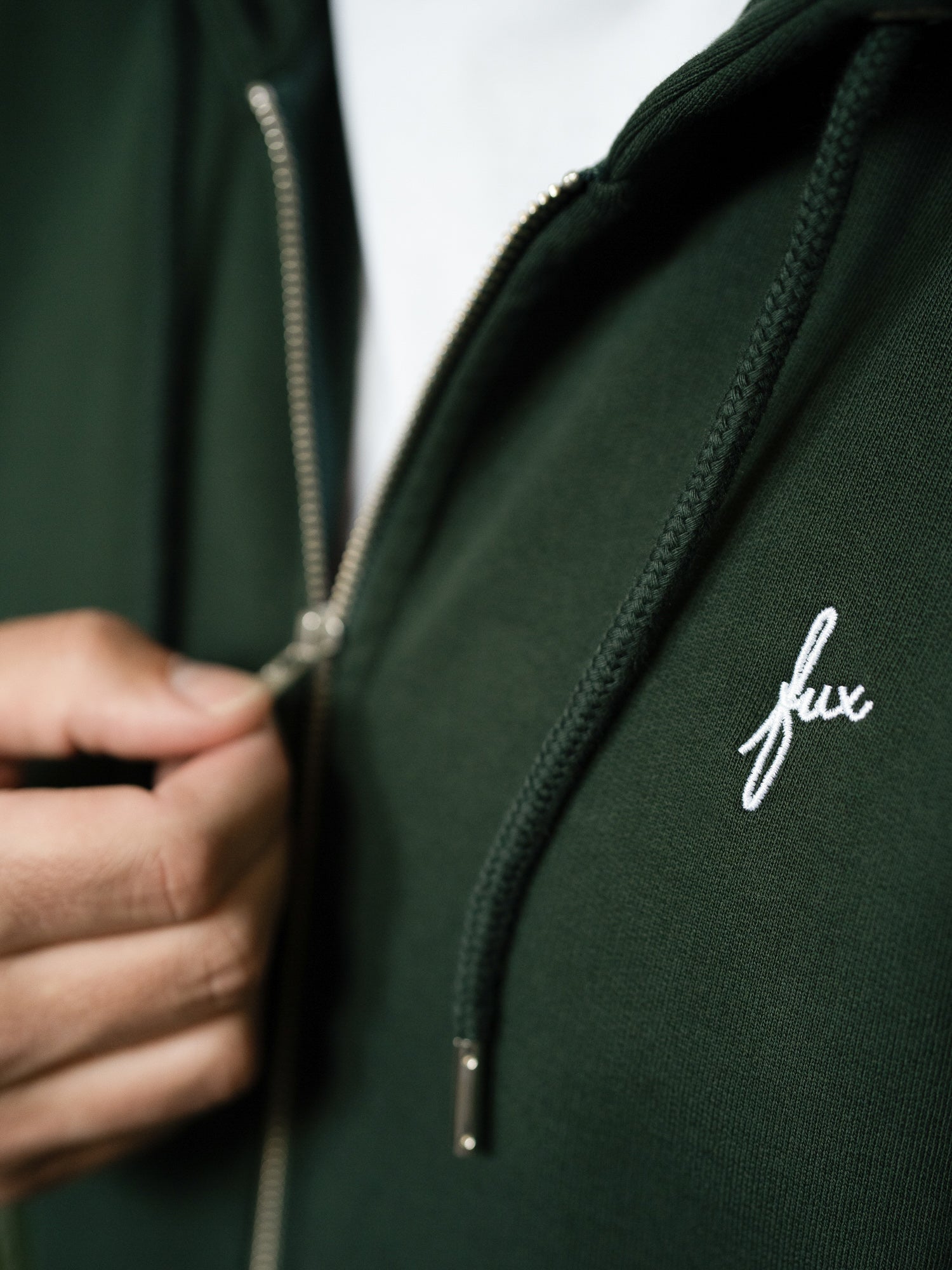 Detailaufnahme FUXBAU Sweatjacke grün – Reißverschluss und Stickerei aus nächster Nähe, gefertigt aus 100% Biobaumwolle in Portugal