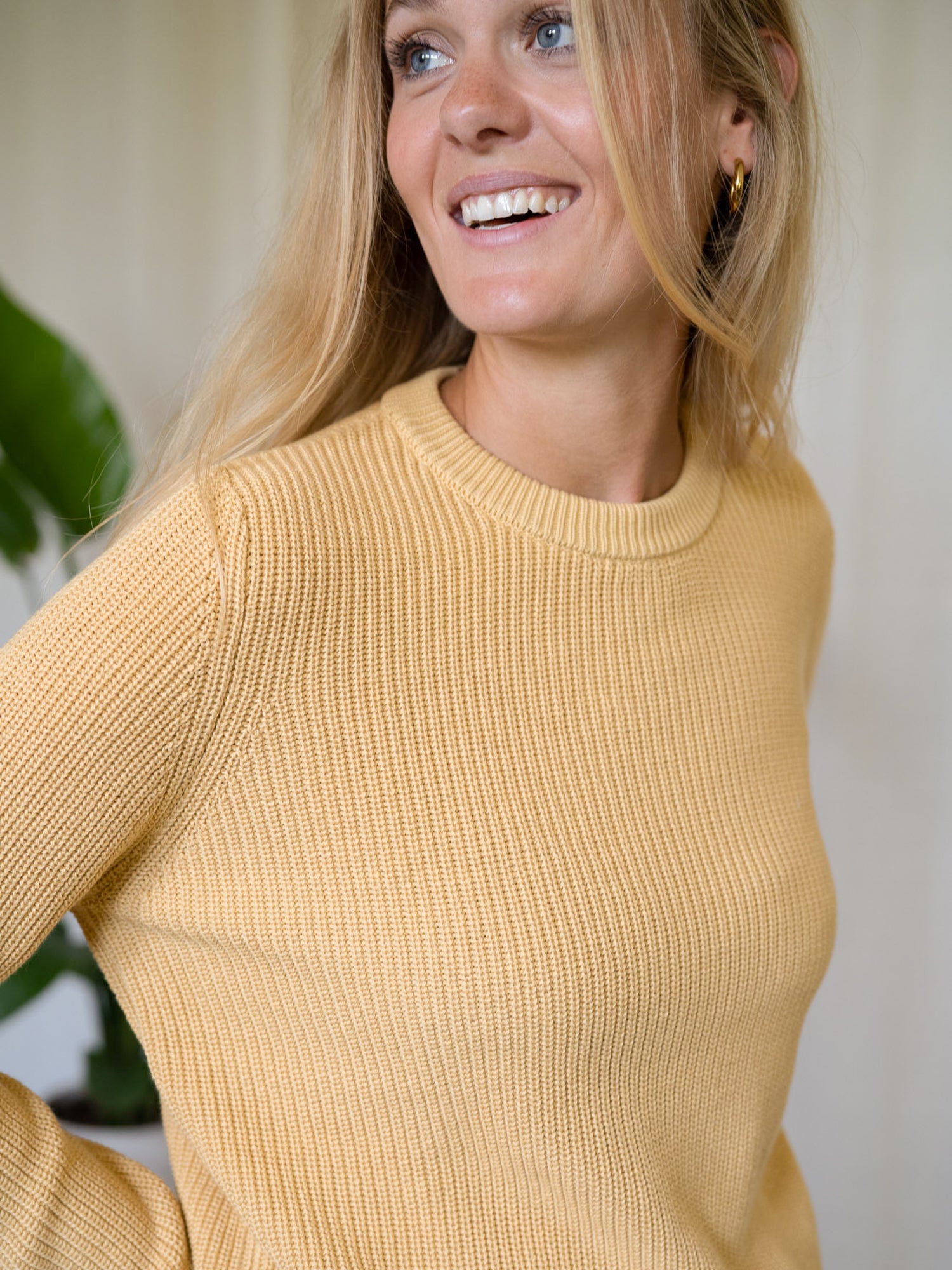 Frontalaufnahme Frau mit gelbem FUXBAU Strickpullover Greta – nachhaltiger 4Seasons Pullover aus Biobaumwolle.