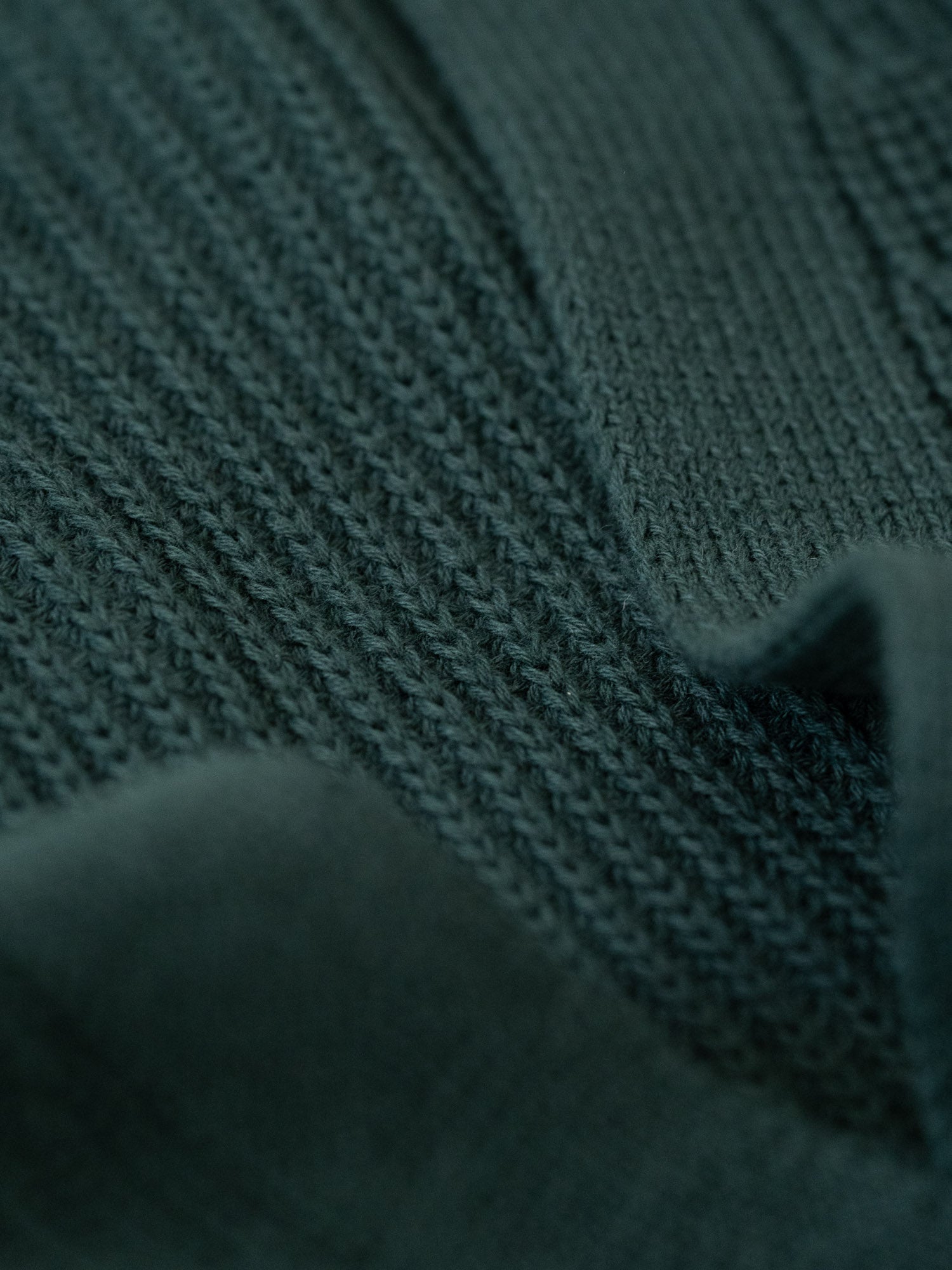 Detailansicht eines Strickmusters von einer nachhaltigen FUXBAU Fair Fashion Strickjacke gefertigt in Italien in dunkelgrün.