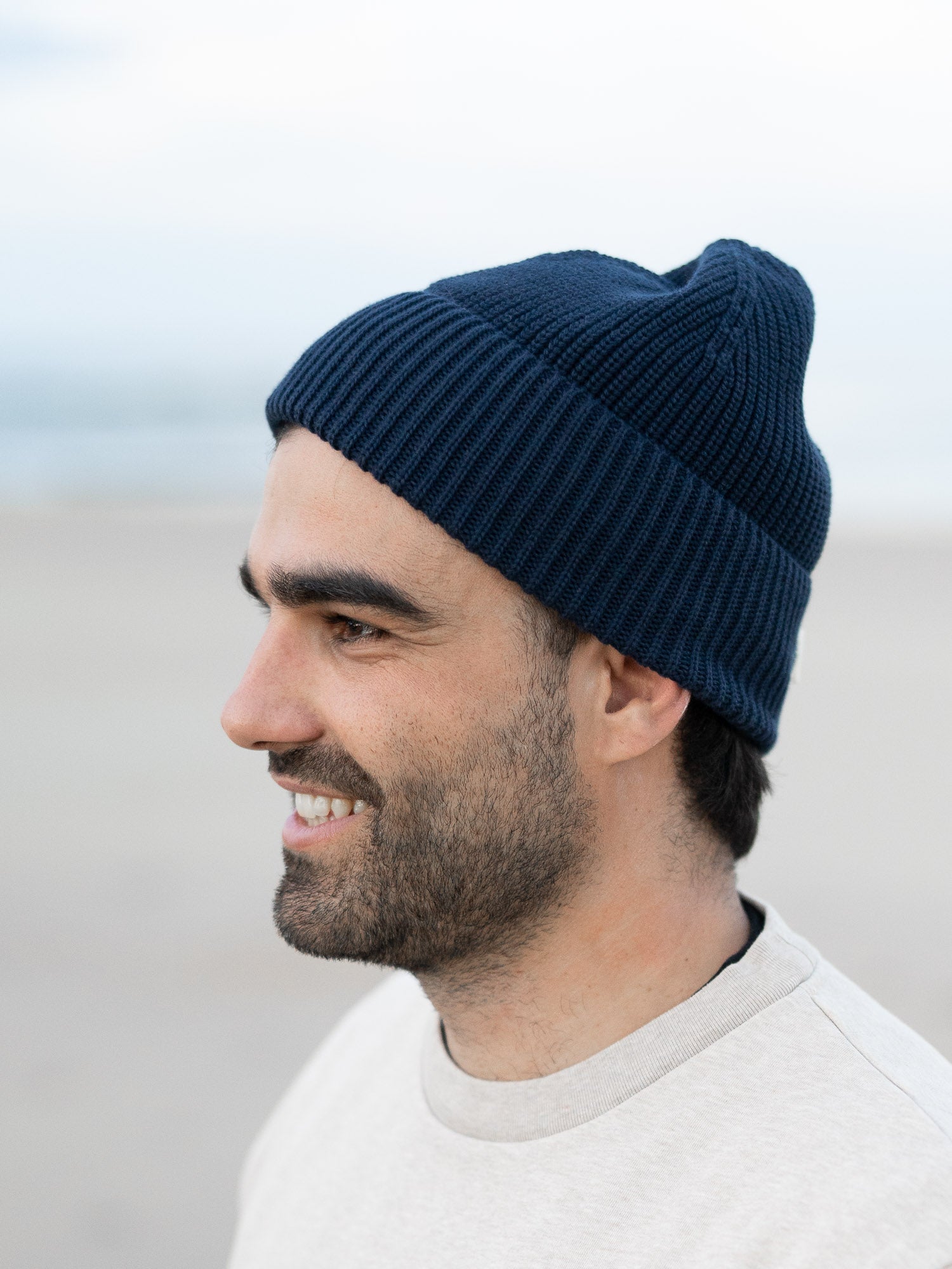 Ein junger Mann trägt eine Strickmütze von FUXBAU aus GOTS zertifizierter Biobaumwolle am Stand in Spanien.