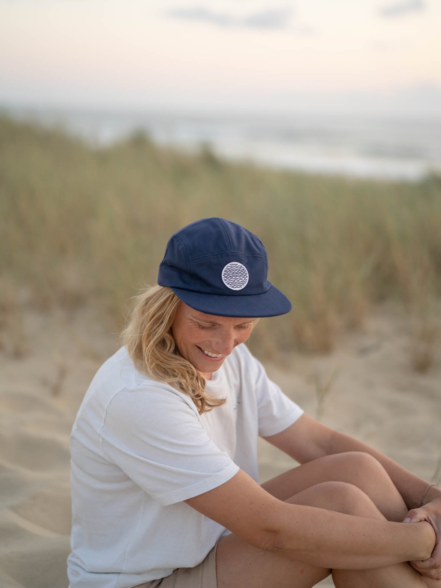 Isi trägt unsere nachhaltige FUXBAU Lost in Lines Cap mit Wellen-Patch am Strand