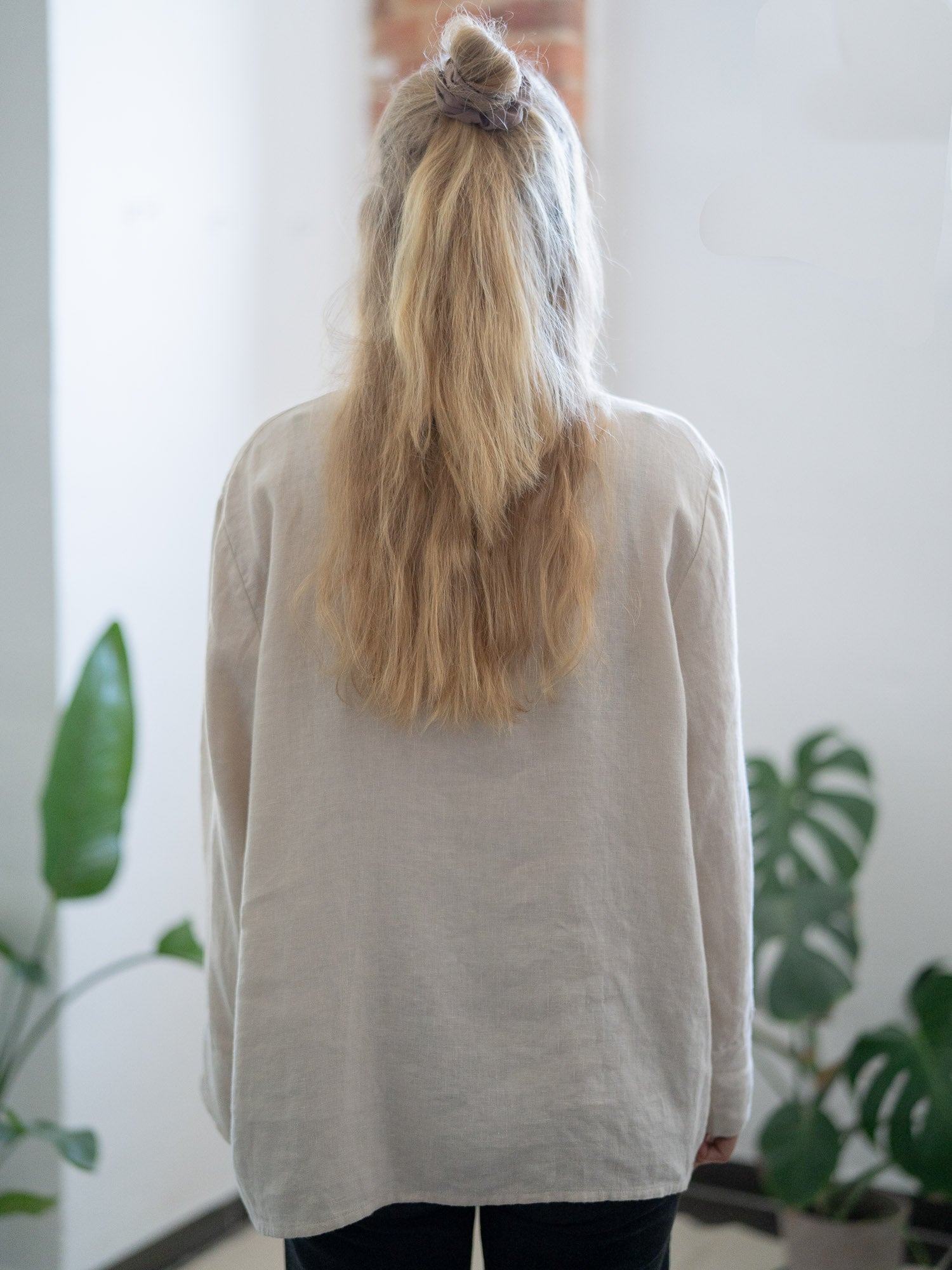 Rückansicht einer nachhaltigen Fair Fashion Frauen Leinenbluse von FUXBAU in cremeweiss aus 100% Leinen gefertigt in Portugal und fairen und nachhaltigen Bedingungen. Getragen von einer jungen, blonden Frau in Münster.