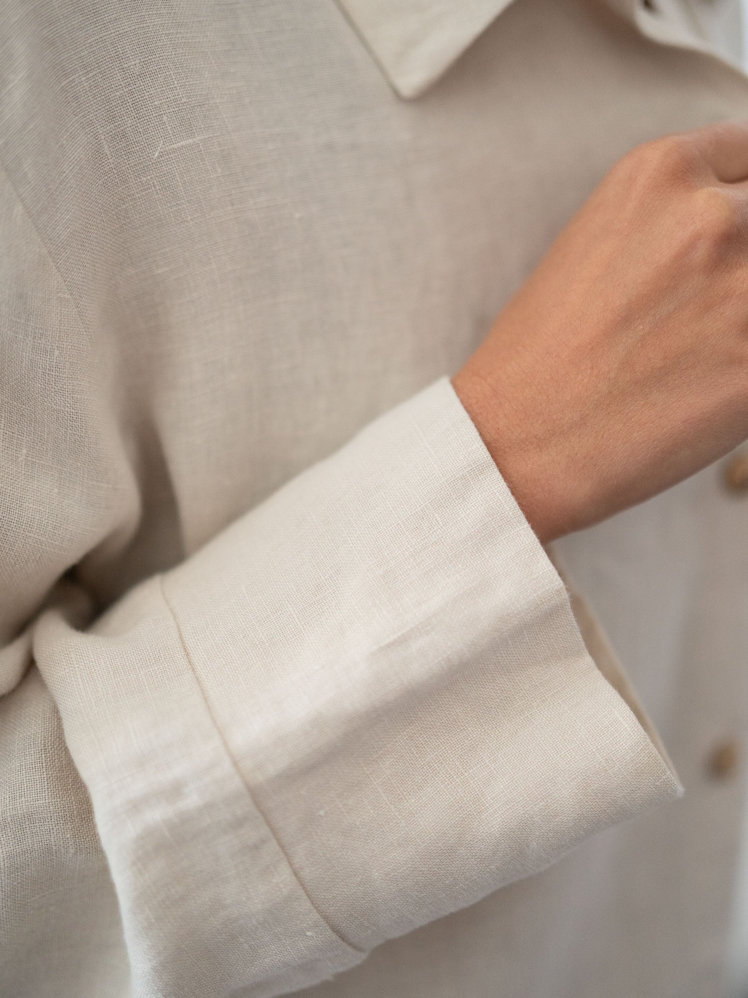 Detailansicht von einem Ärmel einer nachhaltigen Fair Fashion Frauen Leinenbluse von FUXBAU in cremeweiss aus 100% Leinen gefertigt in Portugal und fairen und nachhaltigen Bedingungen. Getragen von einer jungen, blonden Frau in Münster.