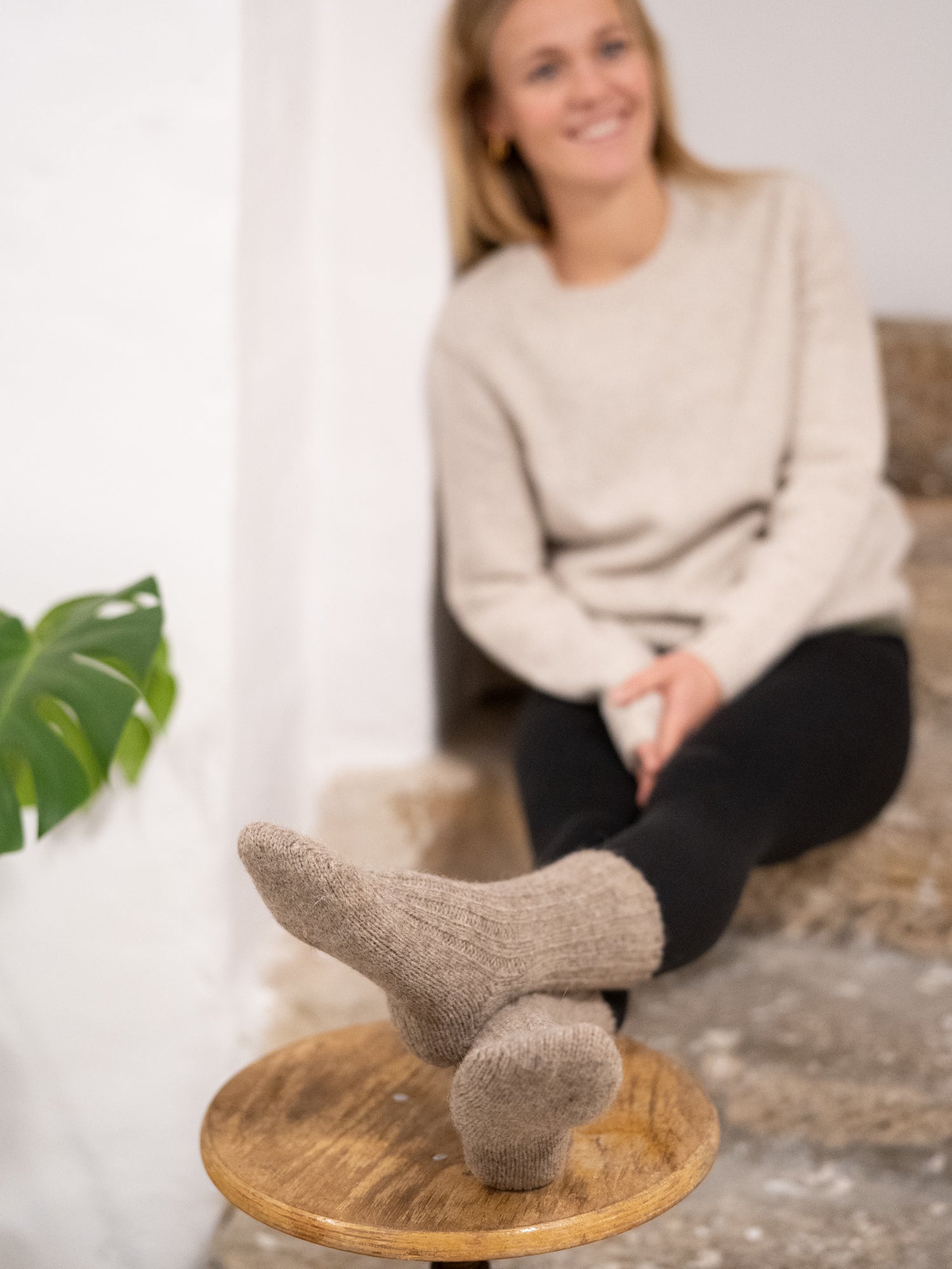 Greta trägt unsere warmen und weichen Alpaka Schafwollsocken in beige.