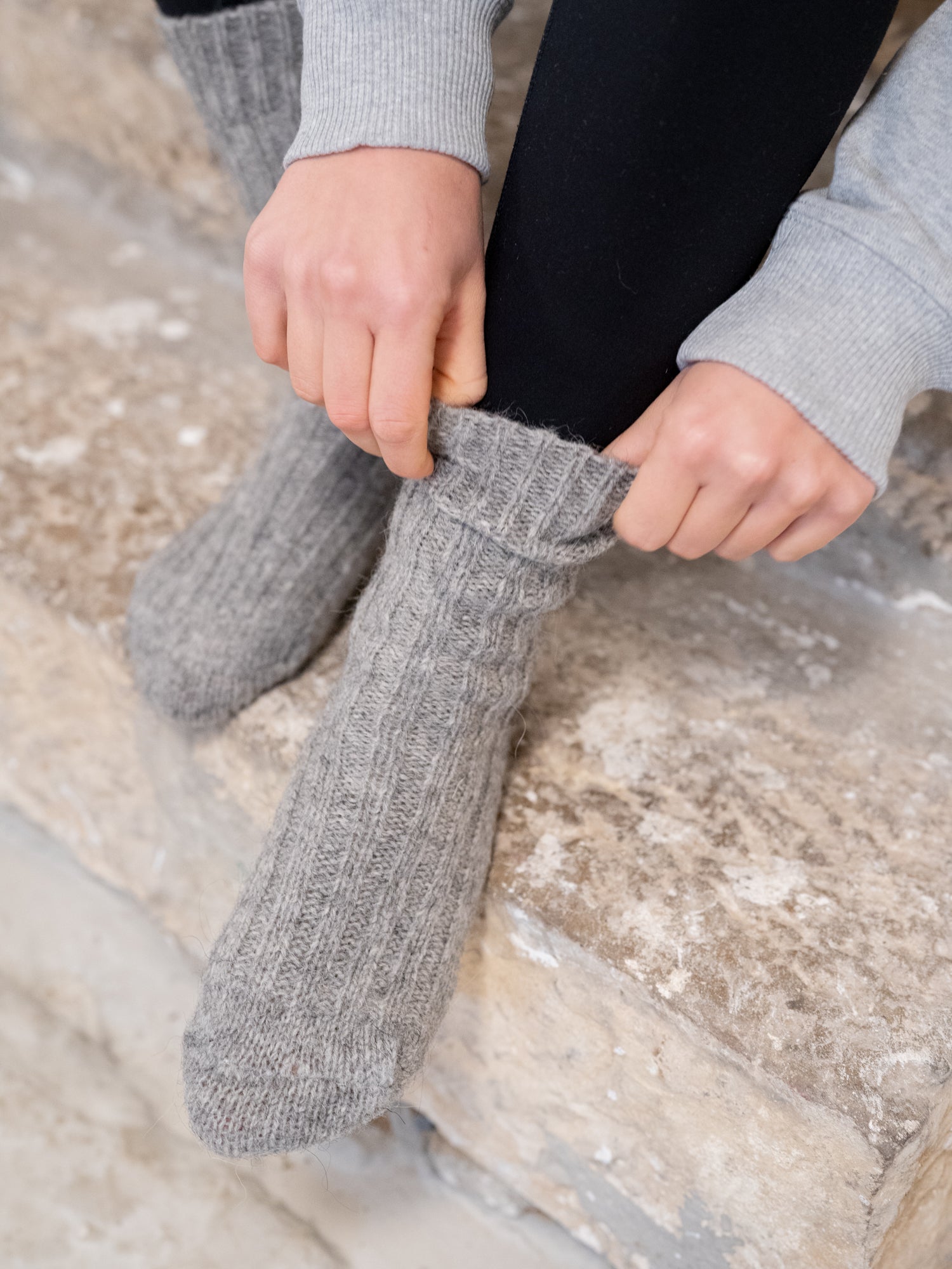 Greta trägt unsere kuschligen und weichen Alpaka Schafwollsocken in grau aus Alpaka und europäischer Schafwolle made in Portugal.