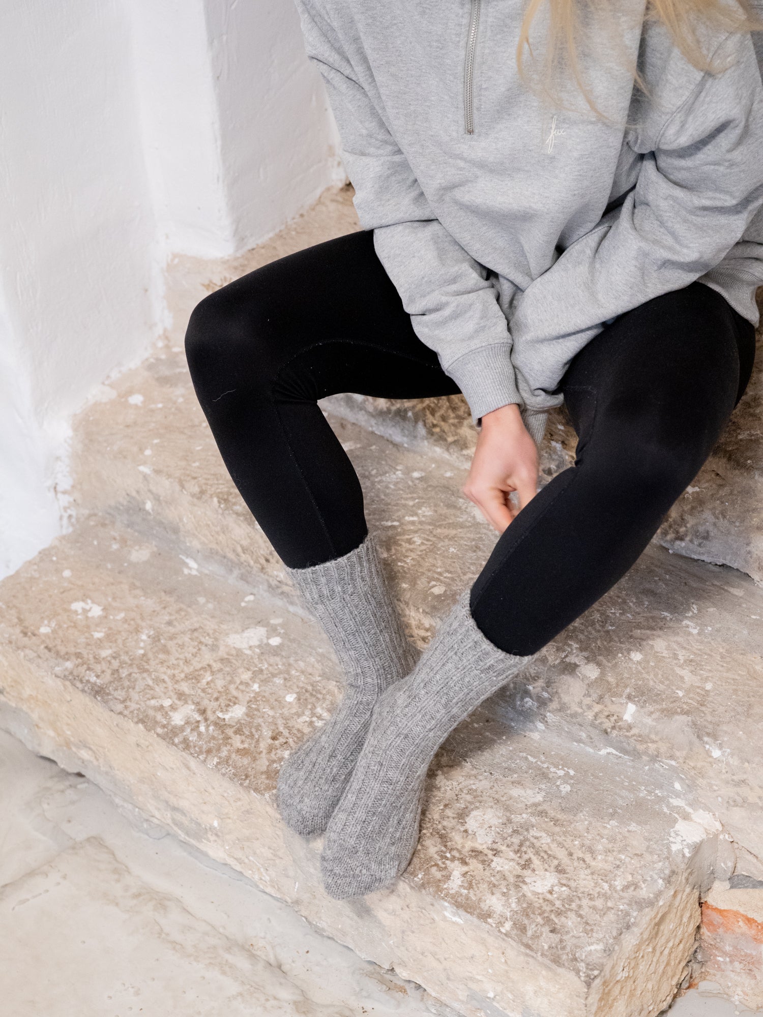 Greta trägt unsere kuschligen und weichen Alpaka Schafwollsocken in grau, die fair und nachhaltig produziert werden