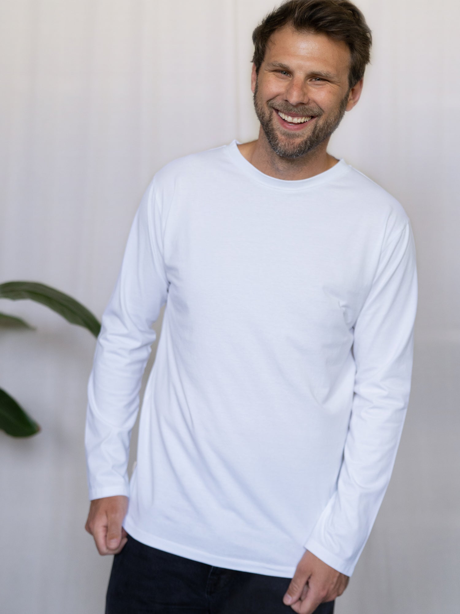 Männer Basic Langarmshirt weiß – Modell lacht und trägt das schlichte Longsleeve aus Bio-Baumwolle, fair hergestellt in Portugal