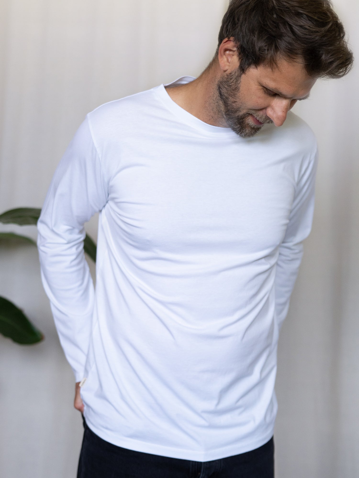 Männer Basic Langarmshirt weiß – Modell mit gesenktem Blick trägt das minimalistische Longsleeve aus GOTS-zertifizierter Biobaumwolle, fair in Portugal