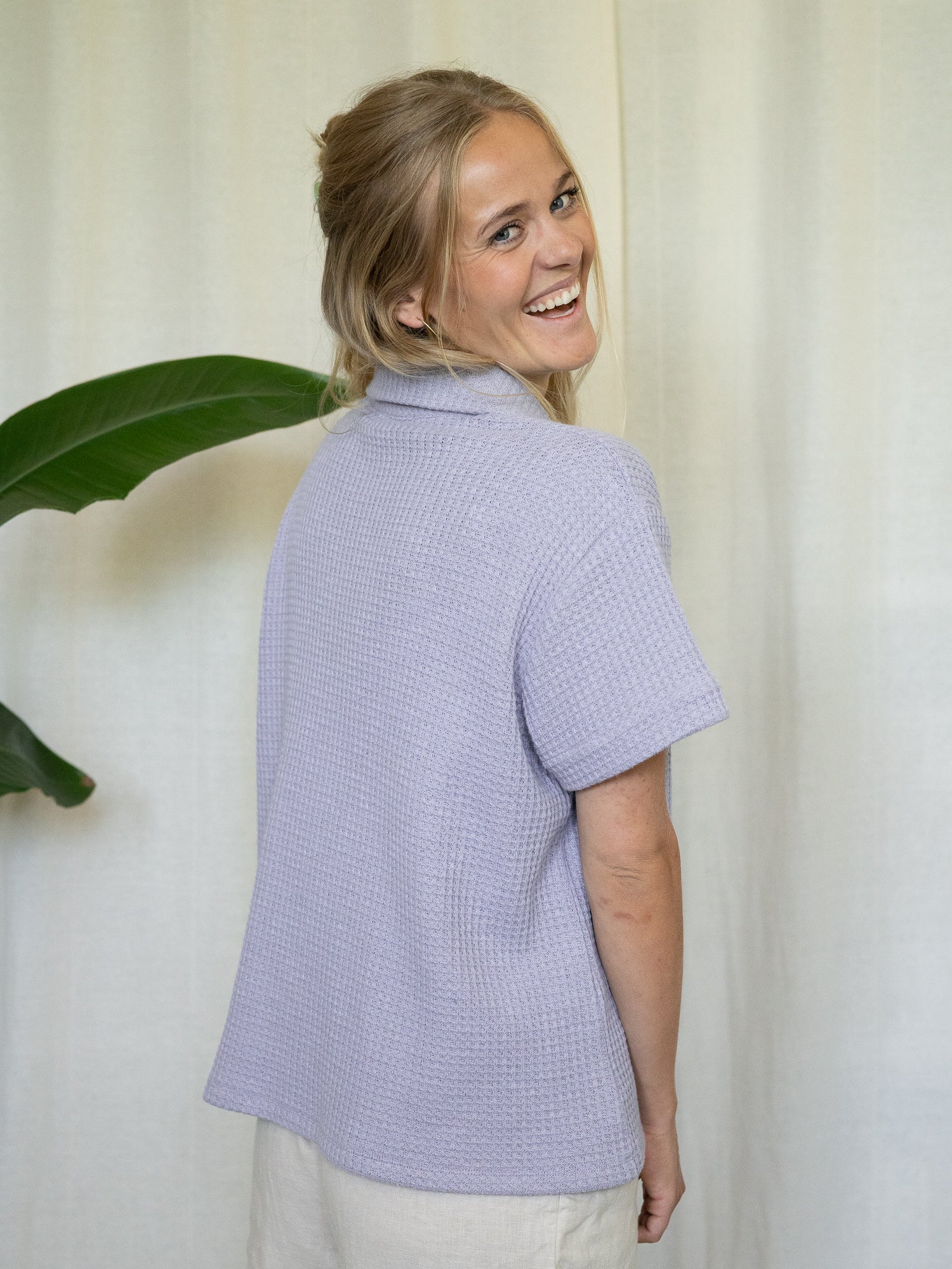 Rückansicht von Greta in der lavendelfarbenen Waffelstrick-Bluse – locker geschnitten und nachhaltig produziert.