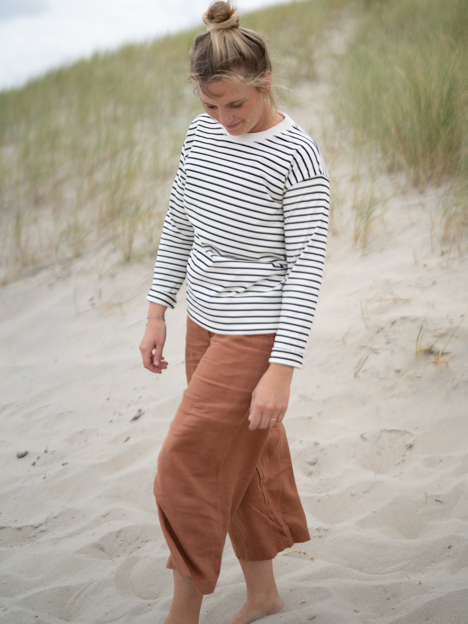 Nachhaltige Damen Leinenhose in Sienna Braun kombiniert mit Streifen Shirt – Fair Fashion Outfit von FUXBAU am Strand fotografiert
