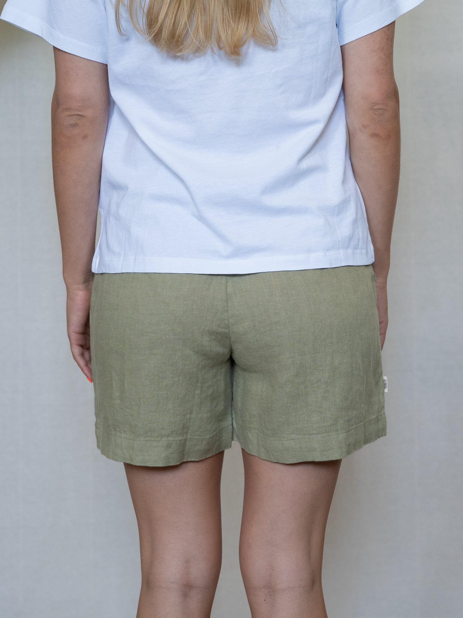 Nachhaltige Fair Fashion Frauen Leinenshorts von FUXBAU in Farbe salbei hellgrün aus 100% Leinen. Getragn von einer jungen, blonden Frau in Größe "S".