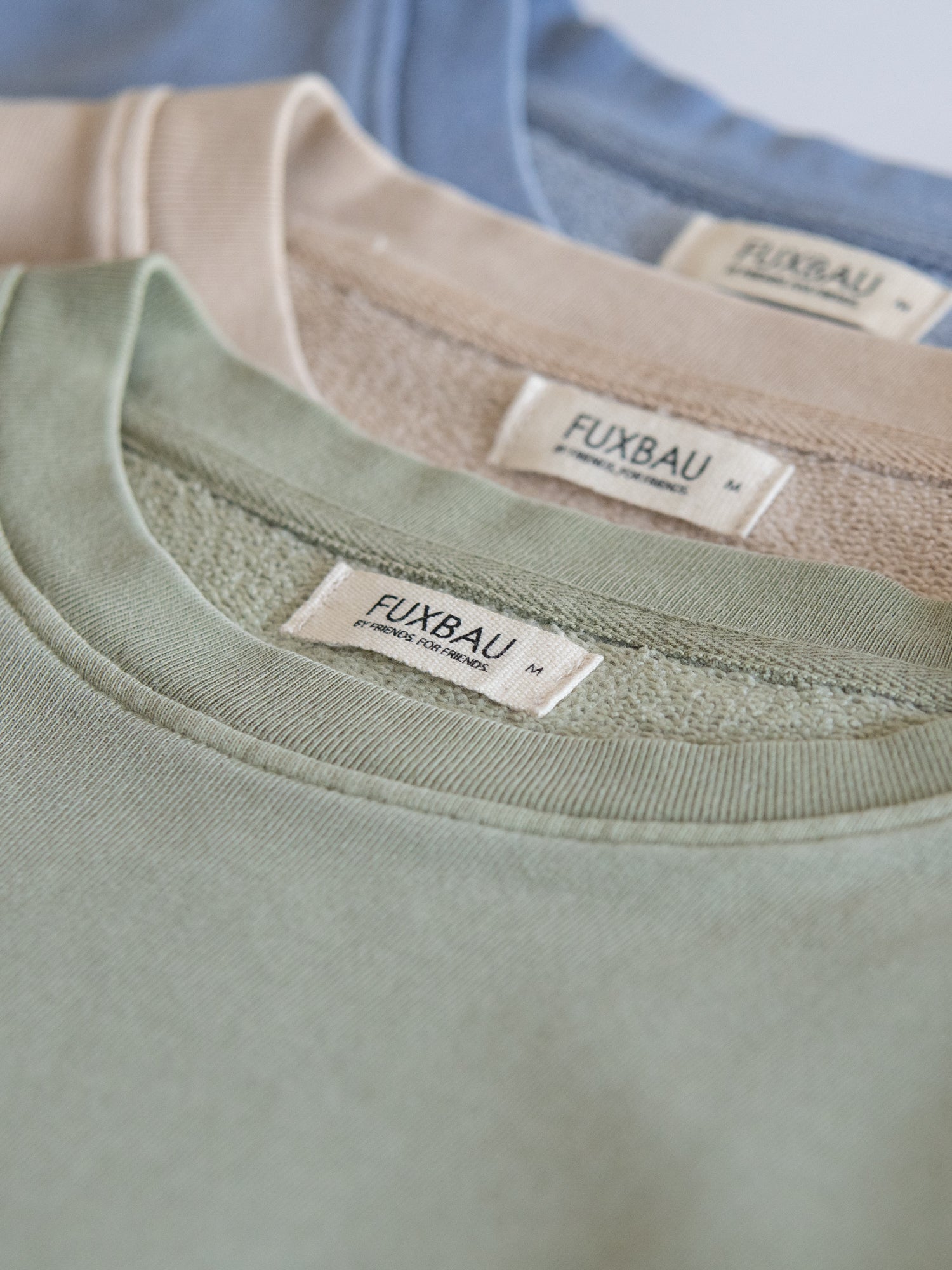 Detailansicht von drei Fair Fashion Frauen oversize Pullovern von FUXBAU in den Farben grün, beige, blau aus 100% Baumwolle.