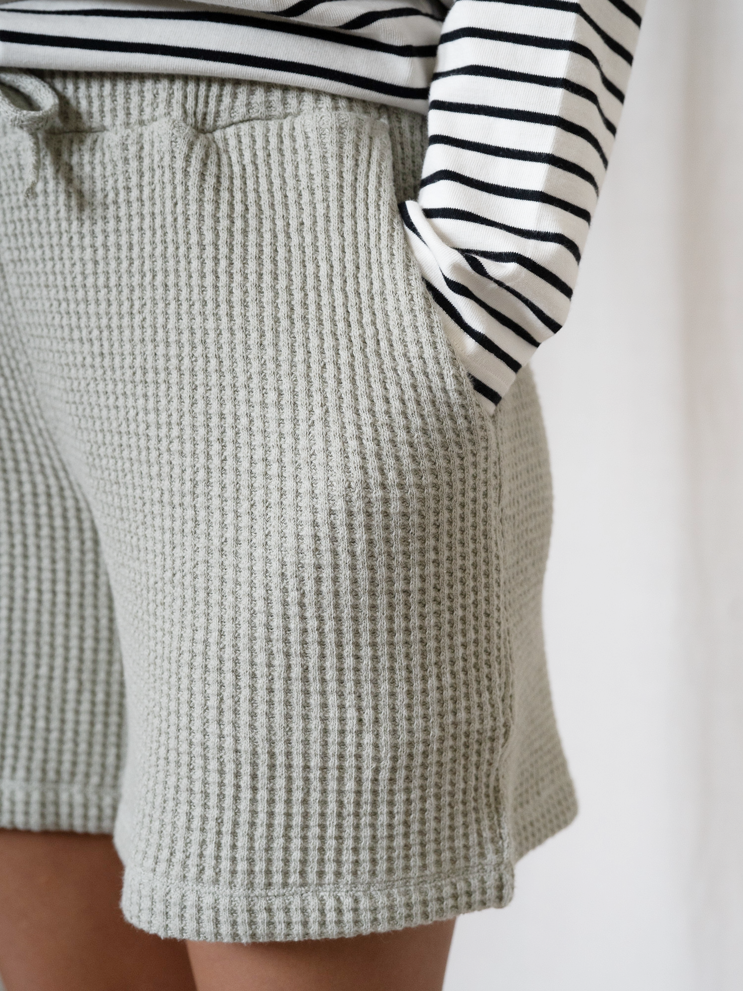 Detailansicht Eingrifftasche und Struktur der salbeigrünen Waffelstrick Shorts – weiche Bio-Baumwolle, fair hergestellt