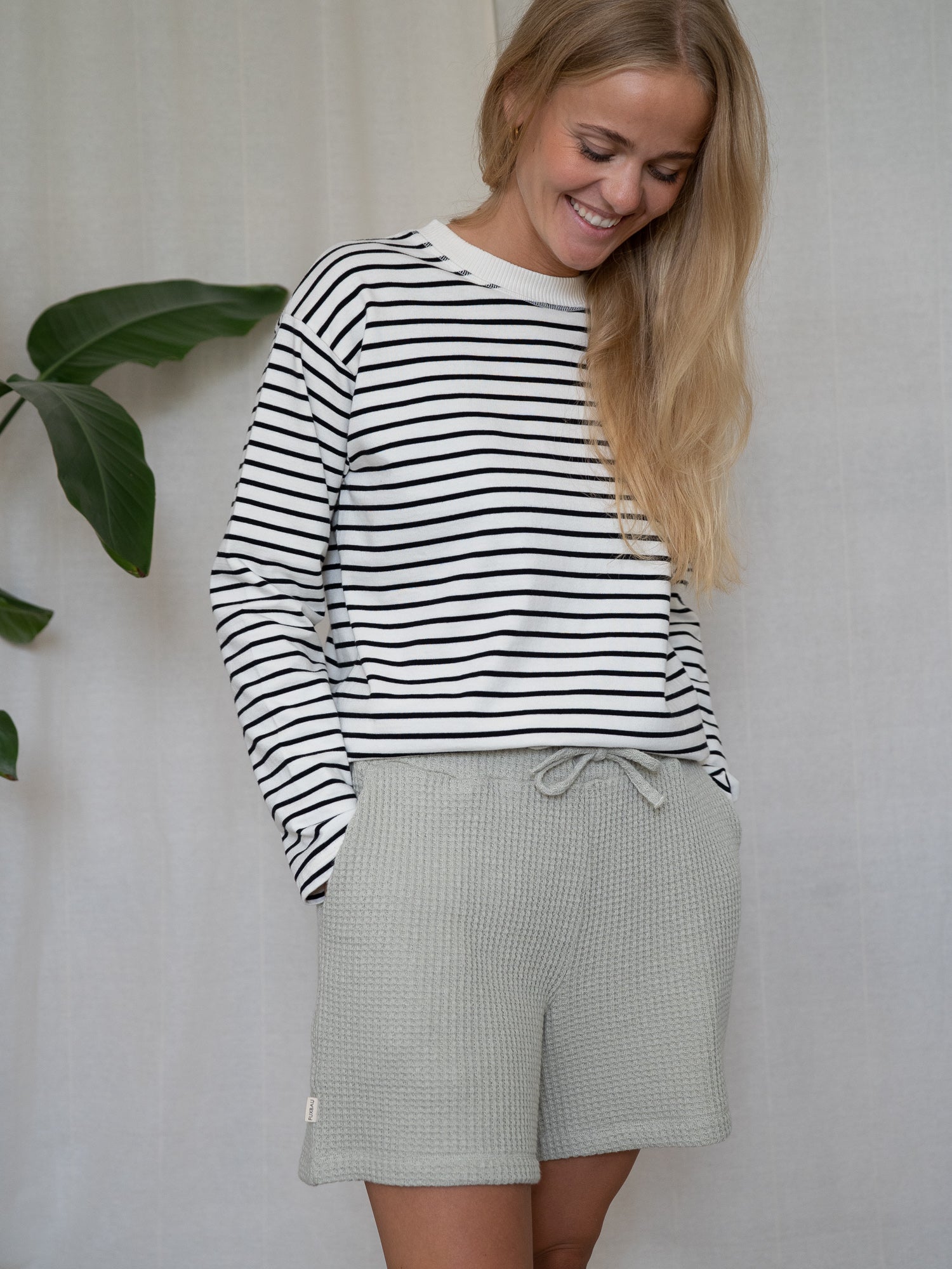 Lächelnde Frau in salbeigrünen Damen Waffelstrick Shorts aus Bio-Baumwolle – GOTS-zertifiziert und produziert in Portugal