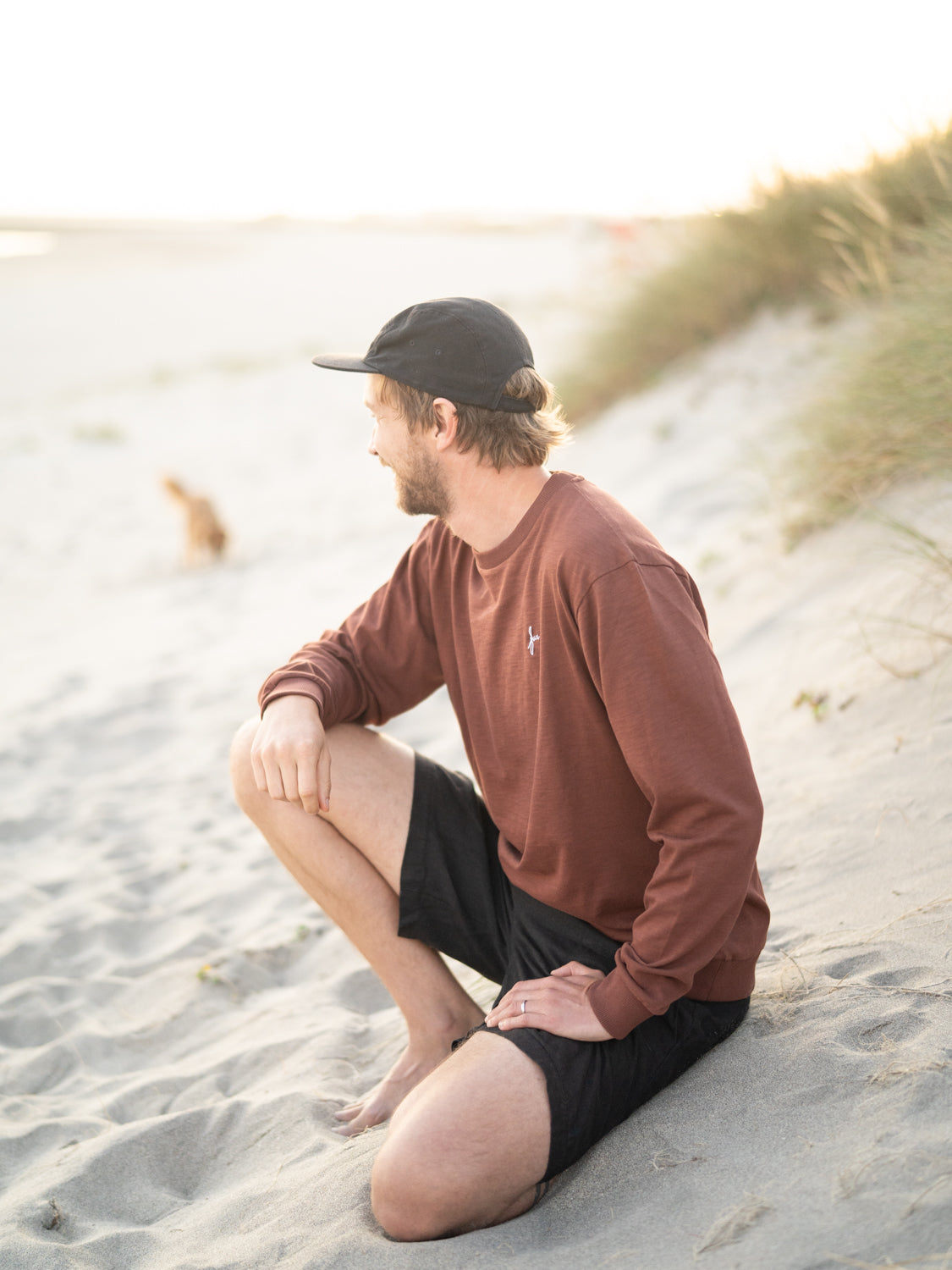 Kenny trägt den Fair Fashion Männer fux Sweater in braun aus 100% GOTS zertifizierter Biobaumwolle am Strand.