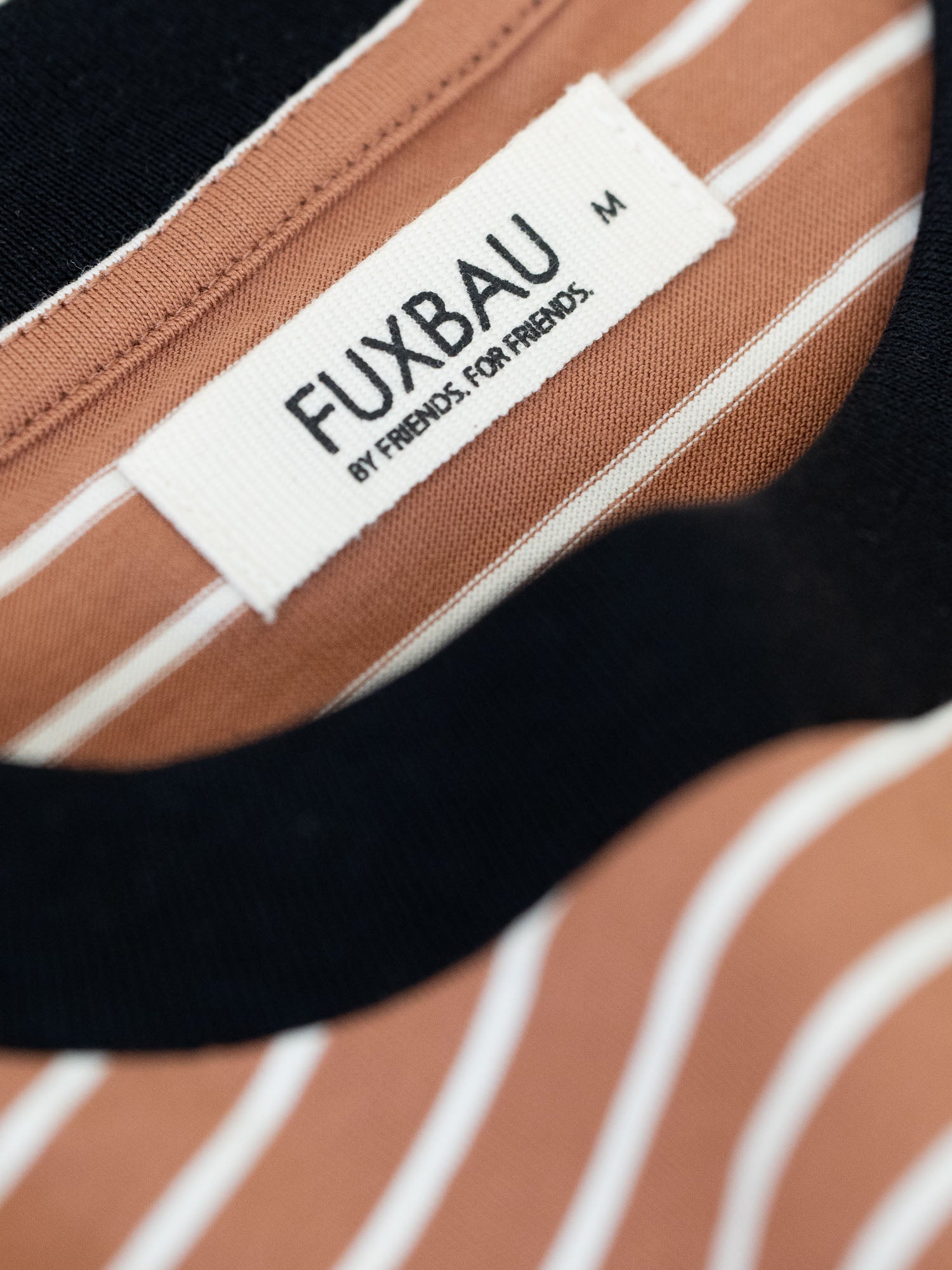 Detailansicht eines gestreiftes FUXBAU Fair Fashion T-Shirt aus Biobaumwolle in schwarz, weiss und karamell.