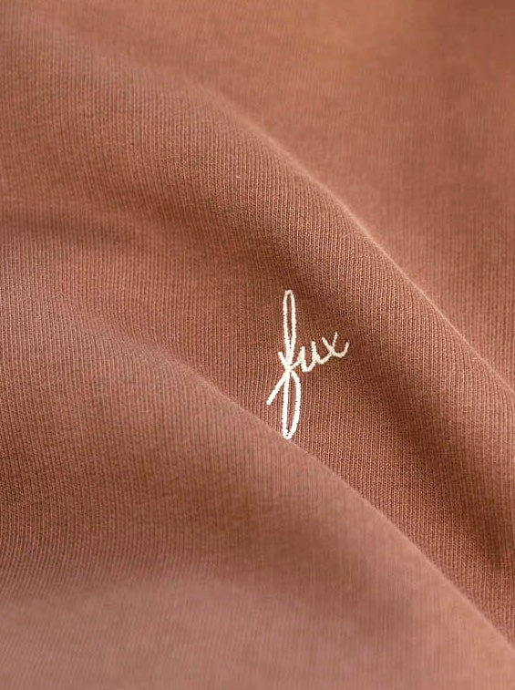 Detailansicht einer weißen fux Stickerei auf einem nachhaltigen FUXBAU Hoodie in karamell