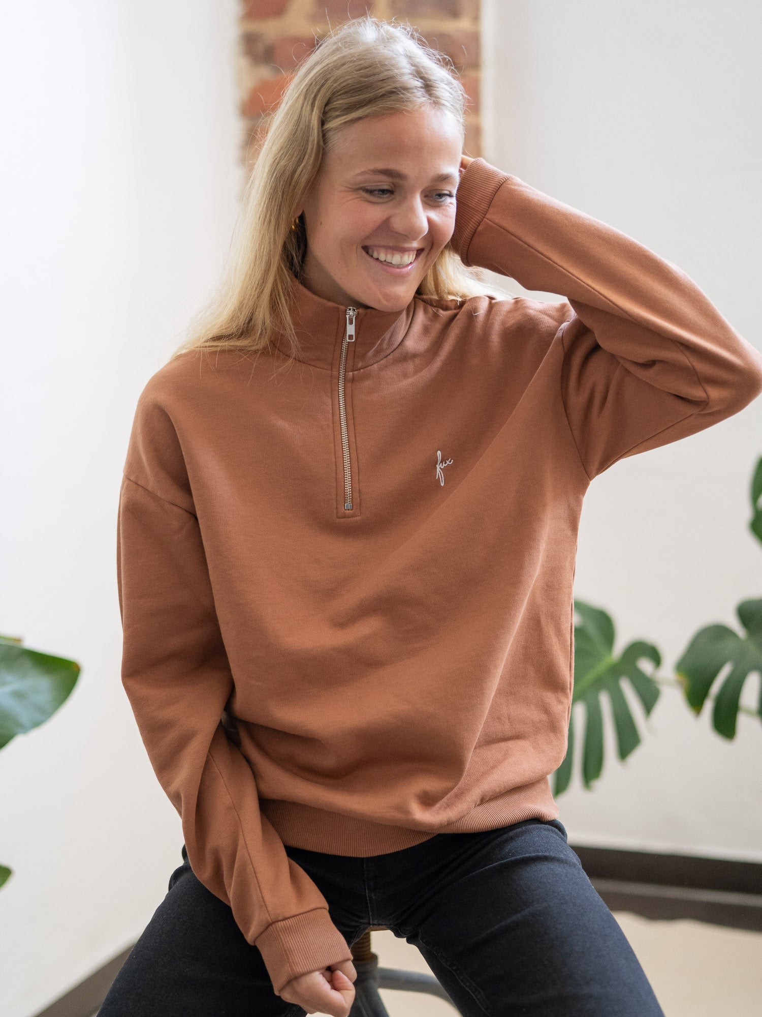 Nachhaltiger Fair Fashion Frauen Half Zip Sweater in karamell von FUXBAU. Gefertigt aus 100% GOTS zertifizierter Biobaumwolle in Portugal. Getragen von einer jungen, blonden Frauen.