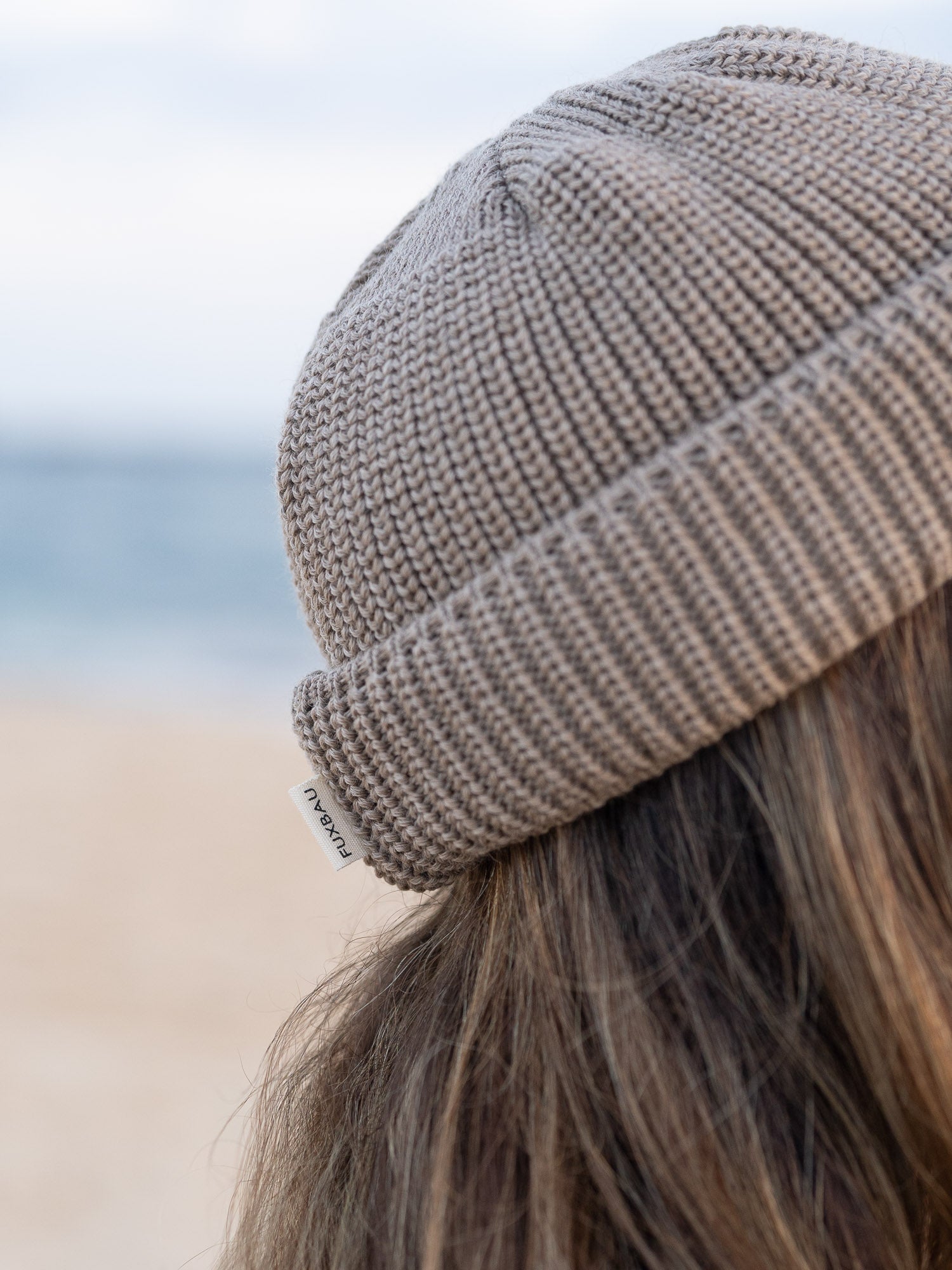 Kurze Merino Fischermütze in der Farbe sand beige aus 100% GOTS zertifizierter Merinowolle. Getragen am Strand in Portugal und fair in Deutschland gefertigt.