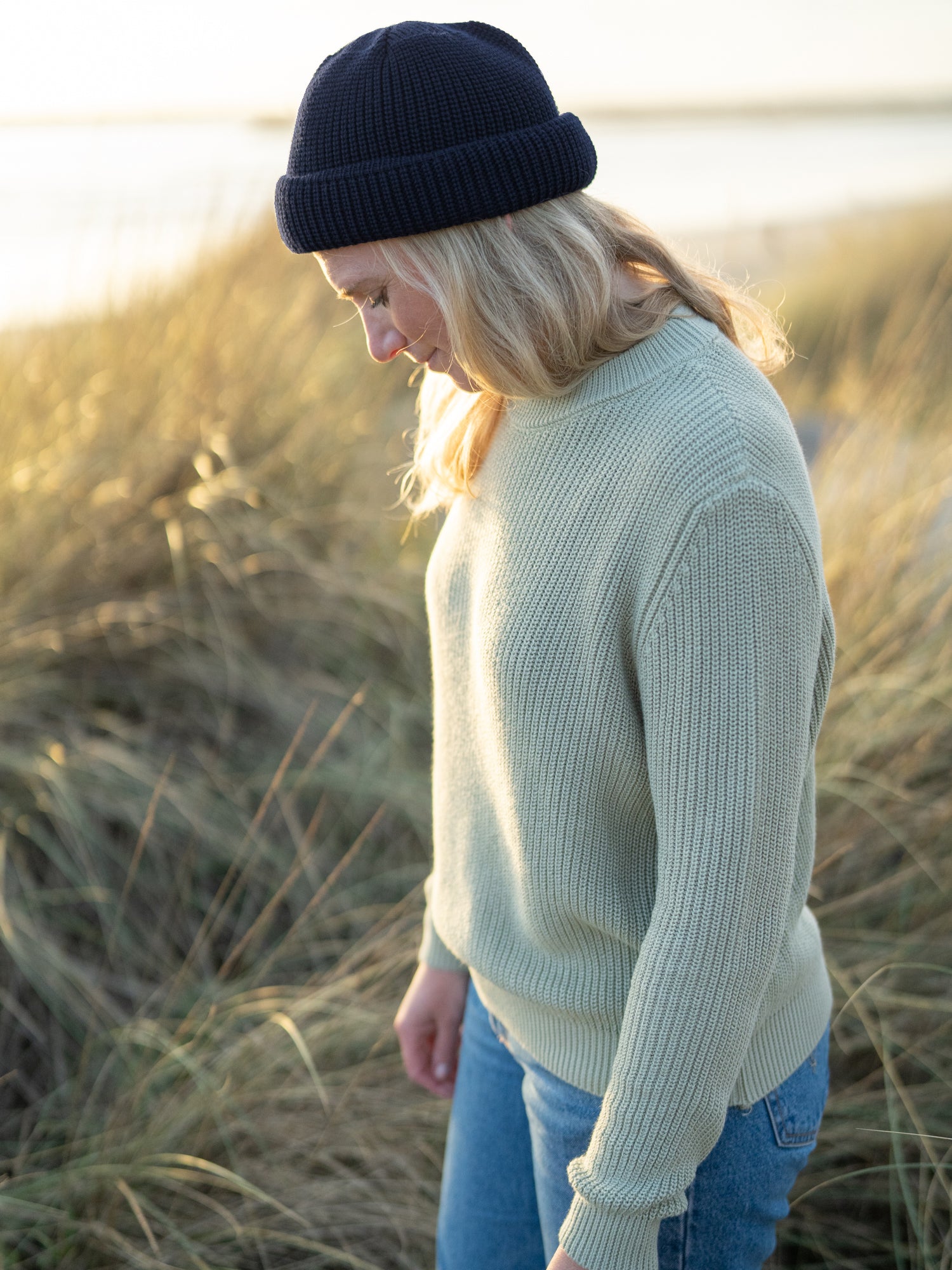 Isi trägt die nachhaltige kurze Fischermütze aus 100% Merinowolle in navy von FUXBAU am Strand