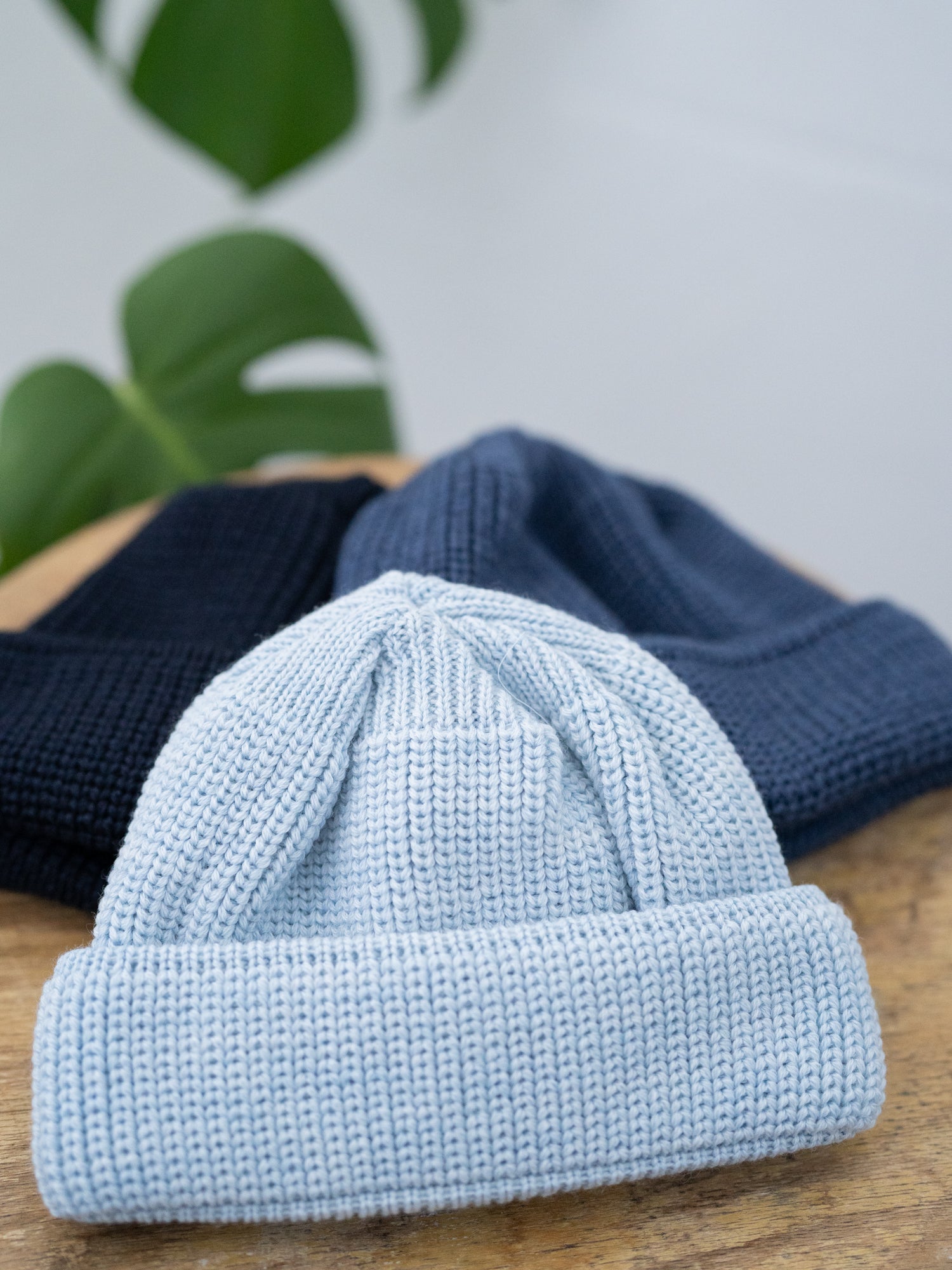 Stapel an nachaltigen FUXBAU Fair Fashion kurzen Merino Fischermützen aus GOTS Merinowolle in Eisblau, nachtblau und navy.