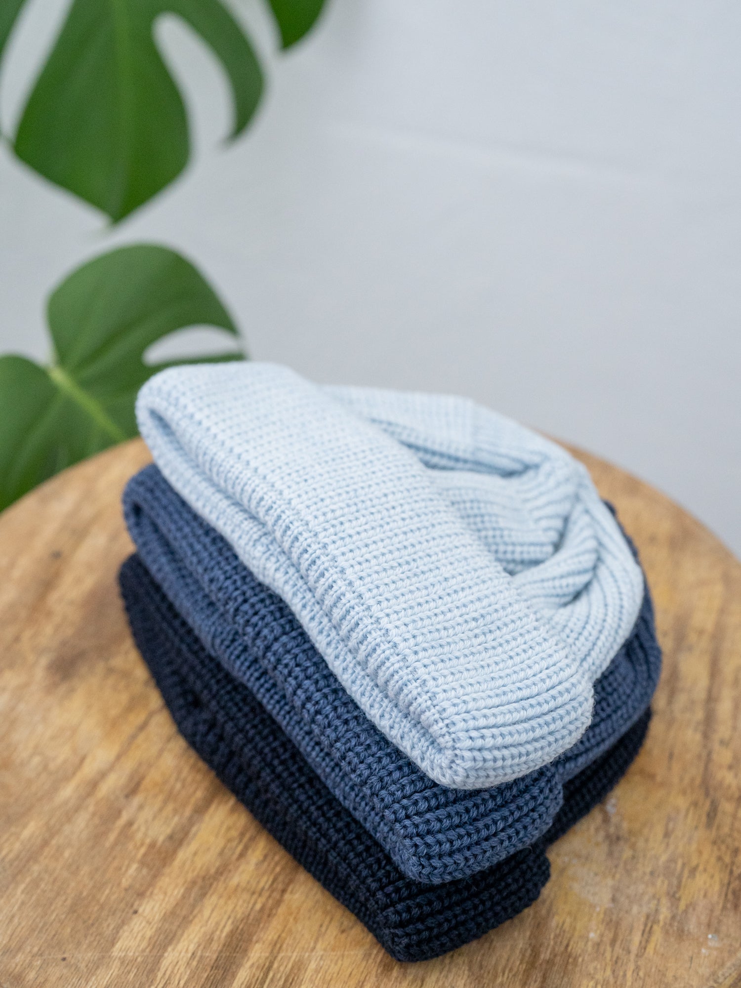 Stapel an nachaltigen FUXBAU Fair Fashion kurzen Merino Fischermützen aus GOTS Merinowolle in Eisblau, nachtblau und navy.