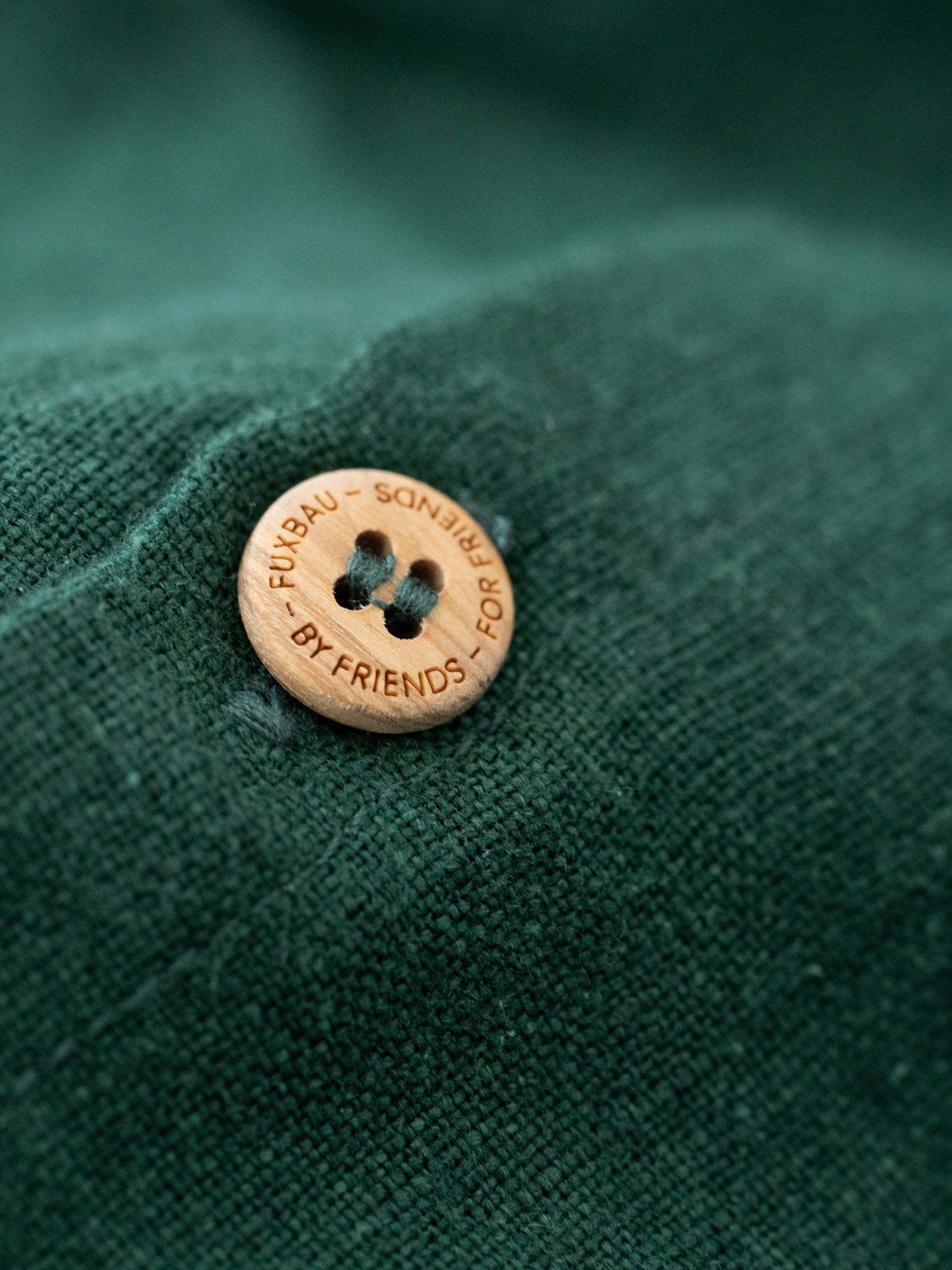 FUBXAU - BY FRIENDS - FOR FRIENDS - Detailbild eines Olivenholz Knopfs mit Branding der Männer Leinenshorts in grün