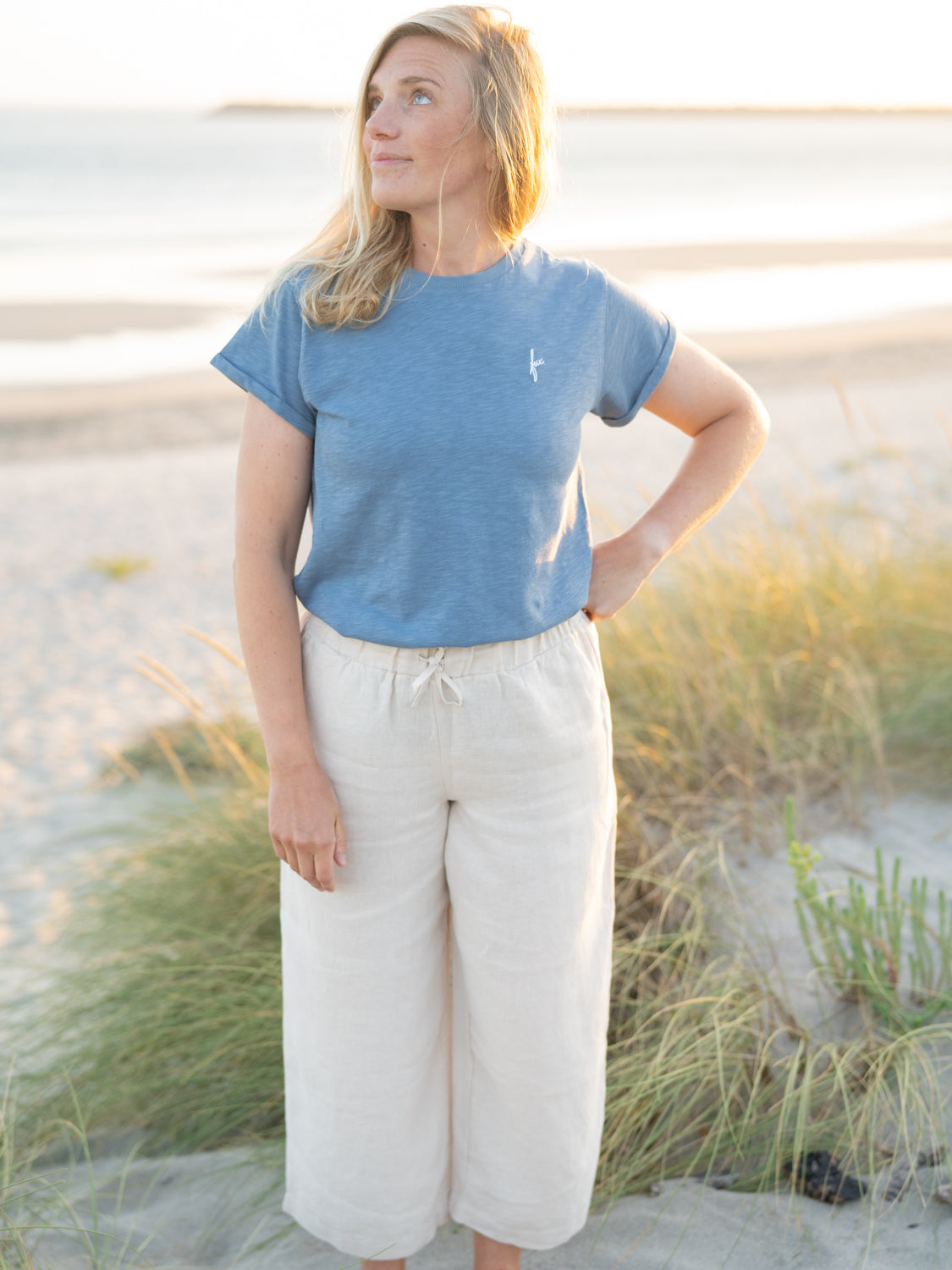 Isi trägt das nachhaltige FUXBAU Frauen fux Azul T-Shirt in blau meliert aus 100% GOTS zertifizierter Biobaumwolle am Strand.