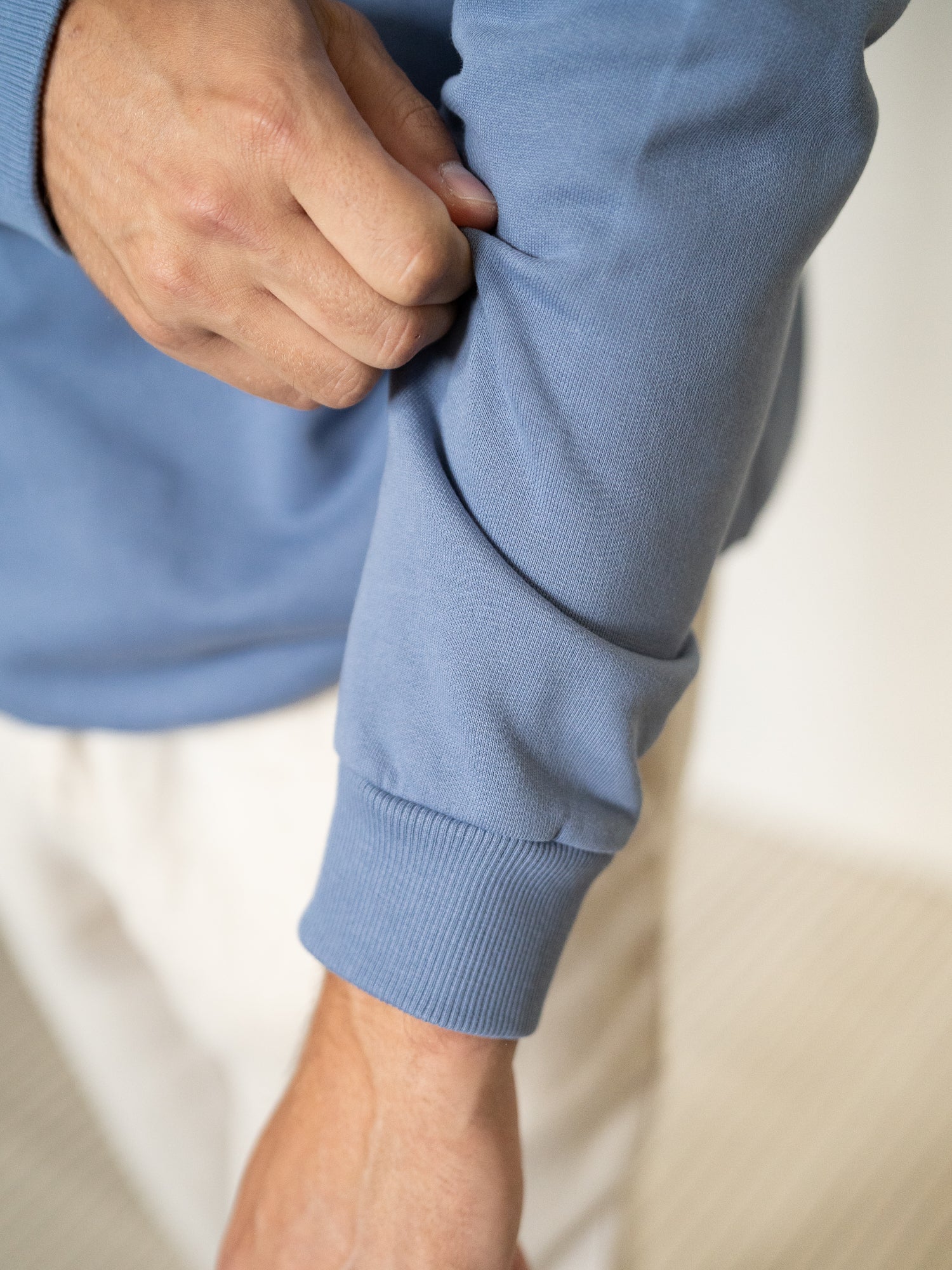 Detailaufnahme vom Ärmelbündchen des Sweaters mit Fokus auf Stoffstruktur und Verarbeitung.