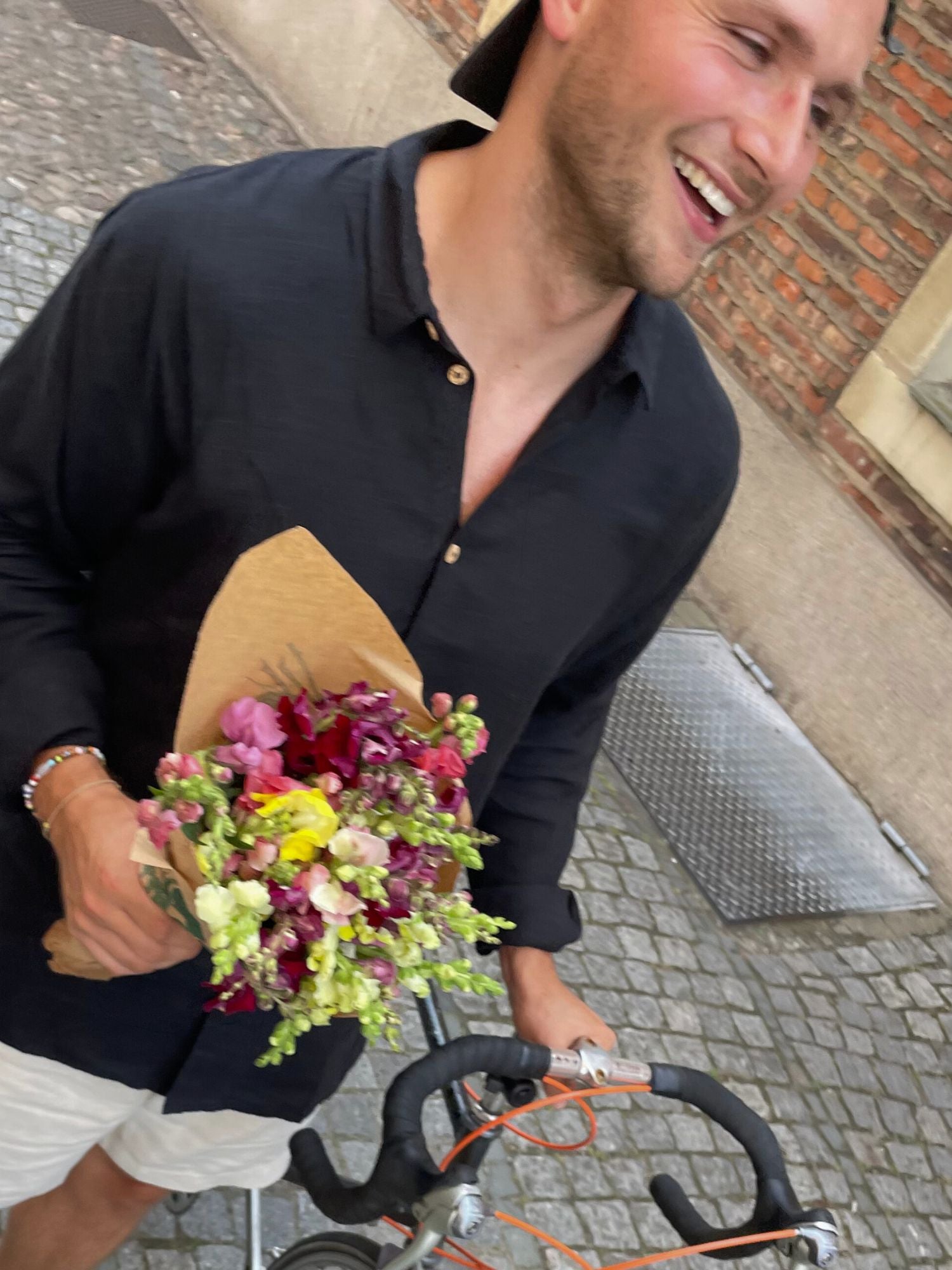 FUXBAU Fair Fashion Männer Leinenhemd Schwarz – nachhaltiges Hemd Fredde, getragen mit Blumenstrauß und Fahrrad, handgefertigt in Portugal