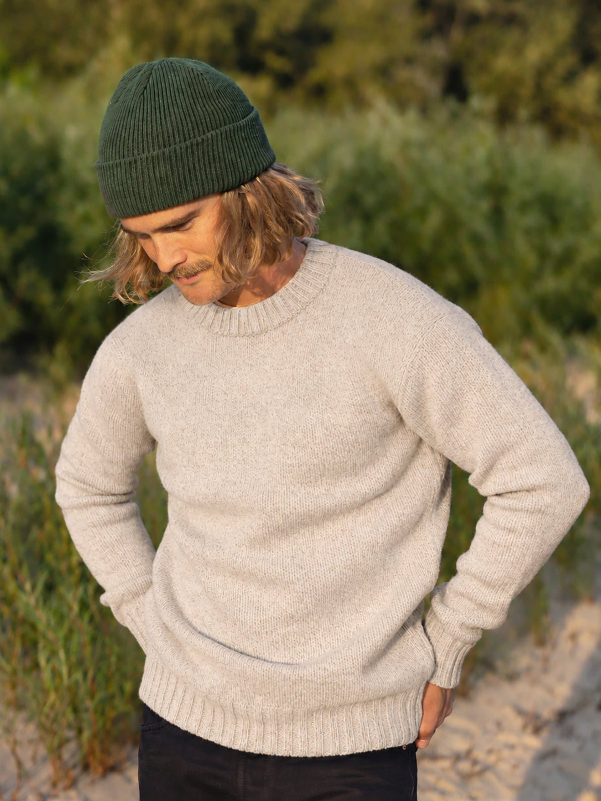 Kelsey trägt unseren Männer Merino Strickpullover in beigemeliert aus 100% Merinowolle und fair in Deutschland hergestellt