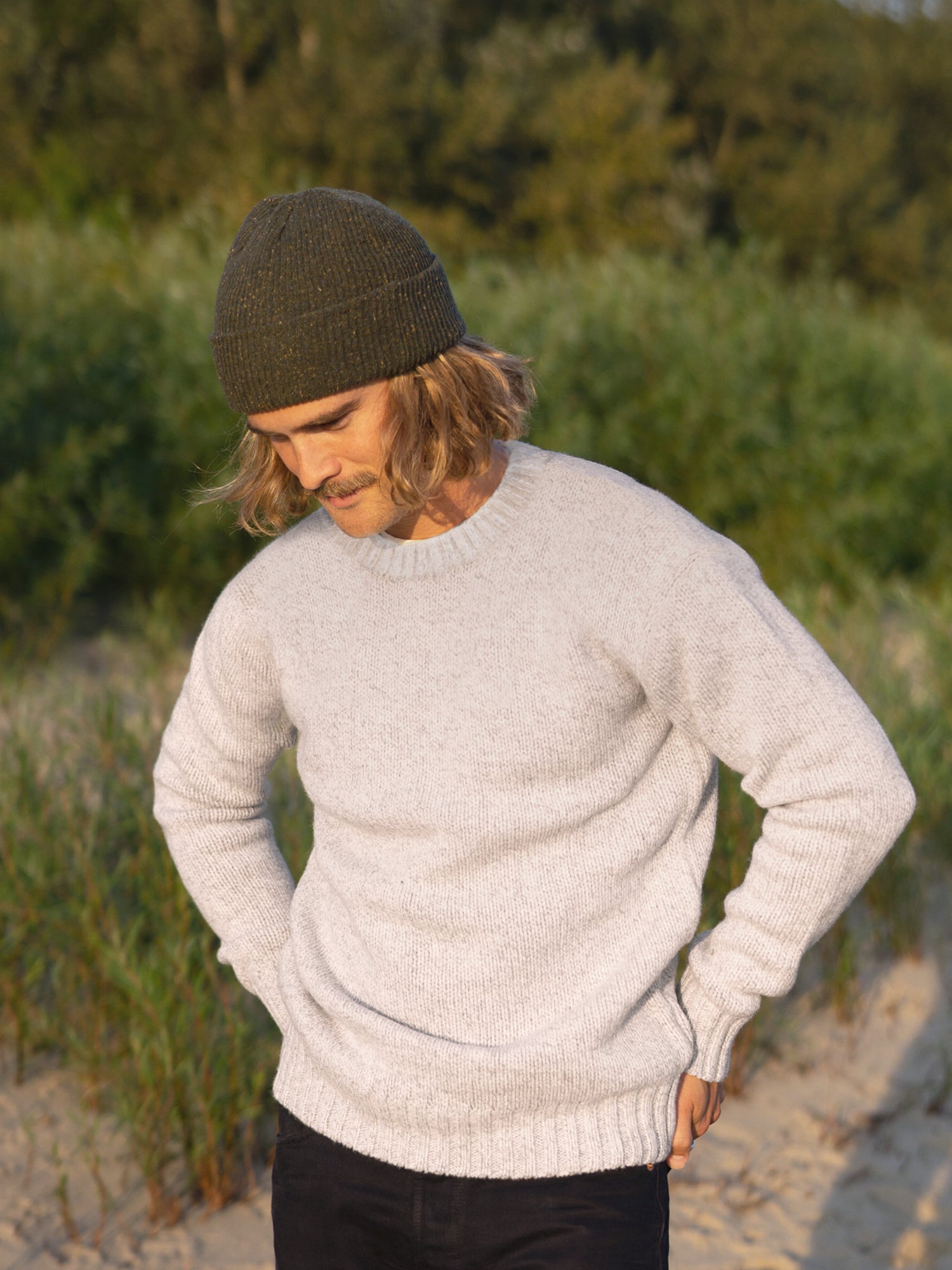 Kelsey trägt unseren nachhaltigen Männer Merino Strickpullover in beige aus 100% Merinowolle und fair in Deutschland hergestellt