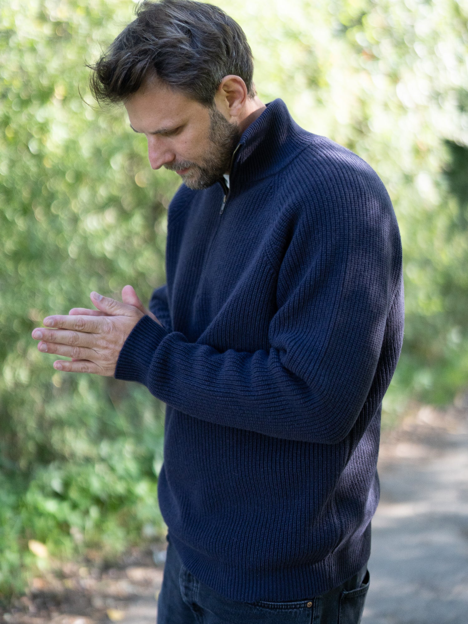 Nachhaltiger Fair Fashion Männer Merino Troyer in navy aus 100% Merino Schurwolle in navy Made in Italy, getragen von einem jungen Mann der sich die Hände reibt.