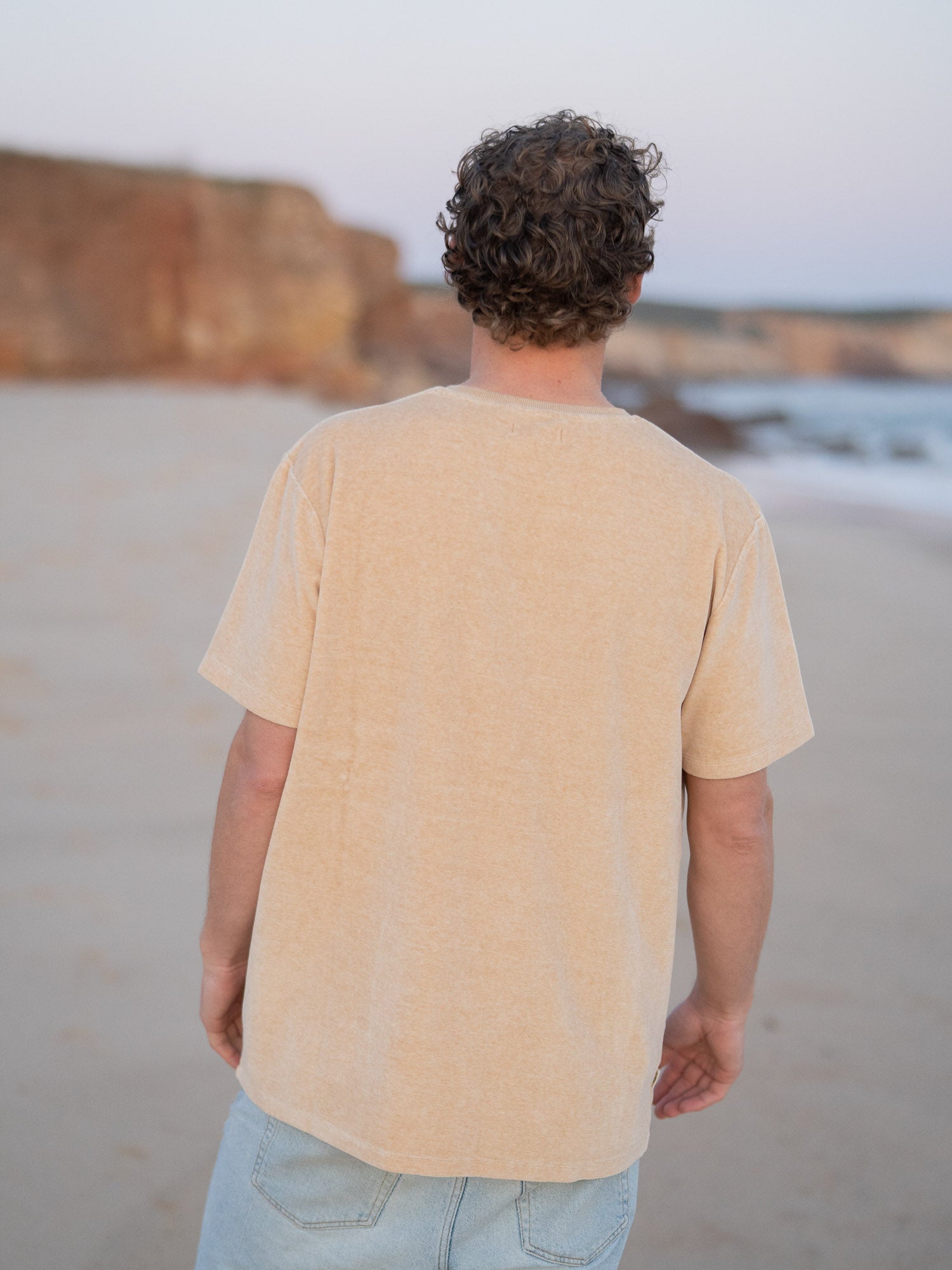 Nachhaltiges Fair Fashion Männer Samt T-Shirt in gelb beige geriffelt aus 100% GOTS zertifizierter Biobaumwolle. Gefertigt in Portugal und getragen am Strand in Portugal.