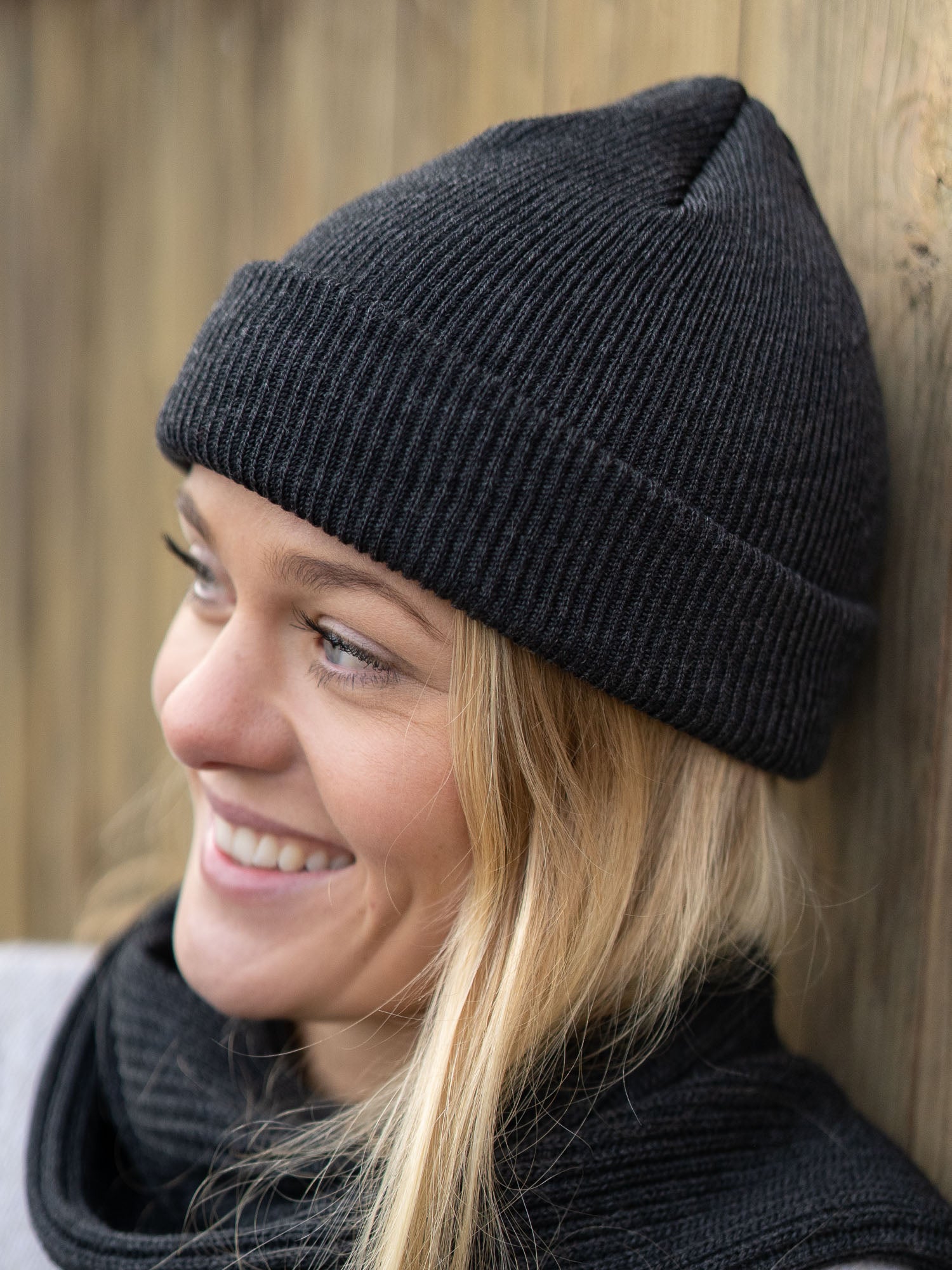 Junge, blonde Frau trägt eine nachhaltig und fair gefertigte Strickmütze von FUXBAU aus 100 % Merino Schurwolle. GOTS zertifiziert und gestrickt in Deutschland.