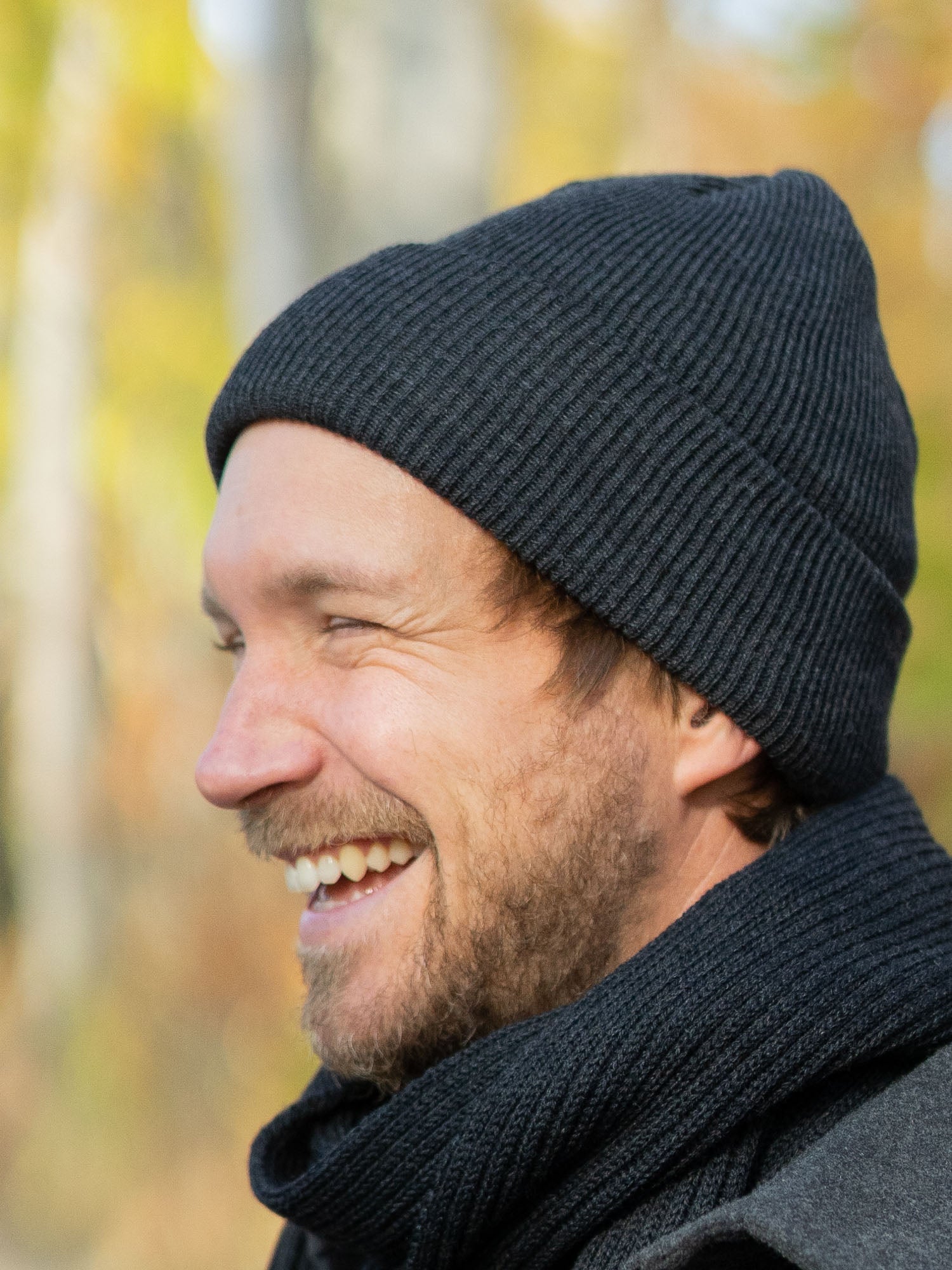 Junger, blonder Mann trägt eine nachhaltig und fair gefertigte Strickmütze von FUXBAU aus 100 % Merino Schurwolle. GOTS zertifiziert und gestrickt in Deutschland.