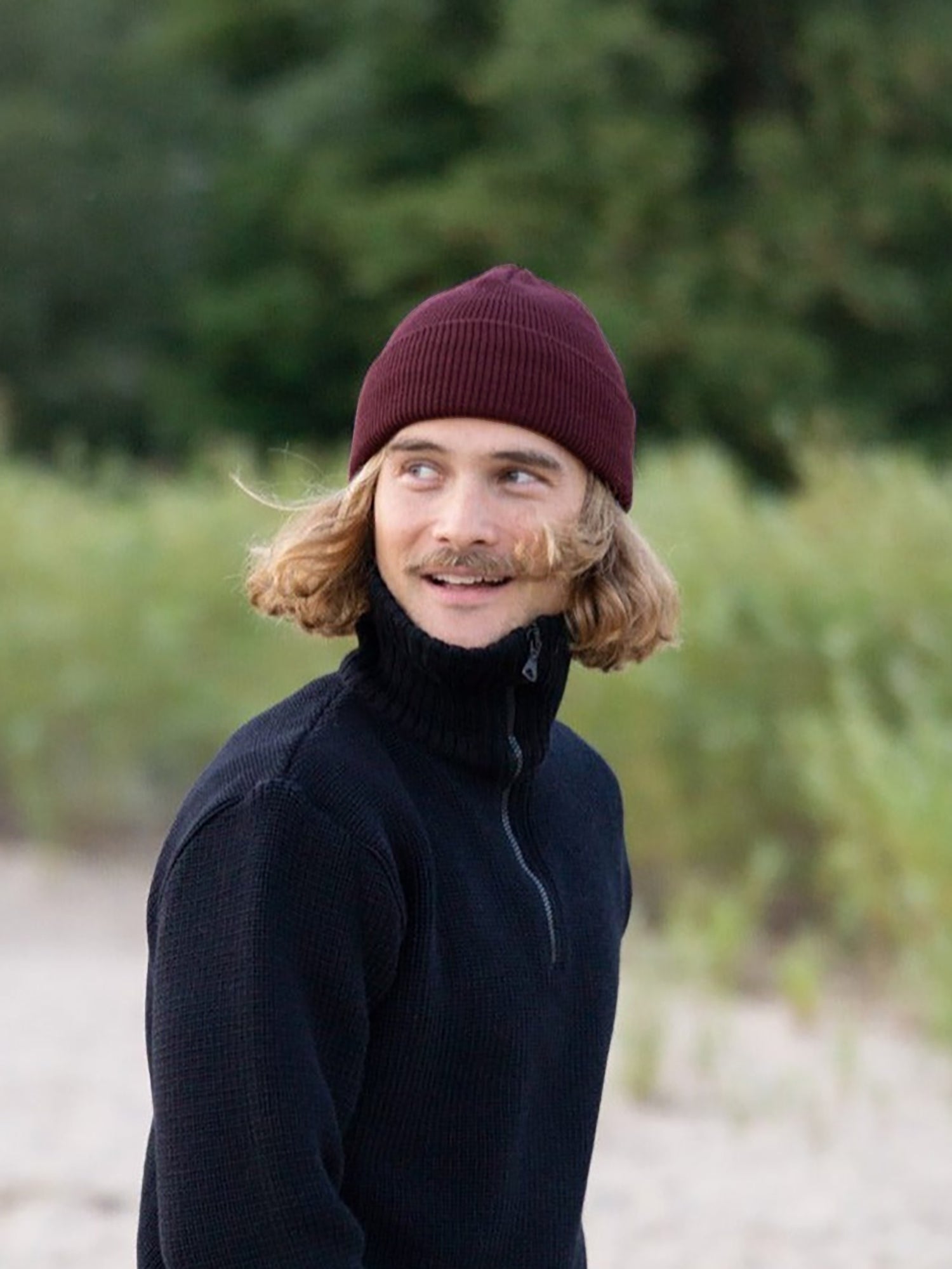 Kelsey trägt unsere Merino Strickmütze in bordaux am Strand