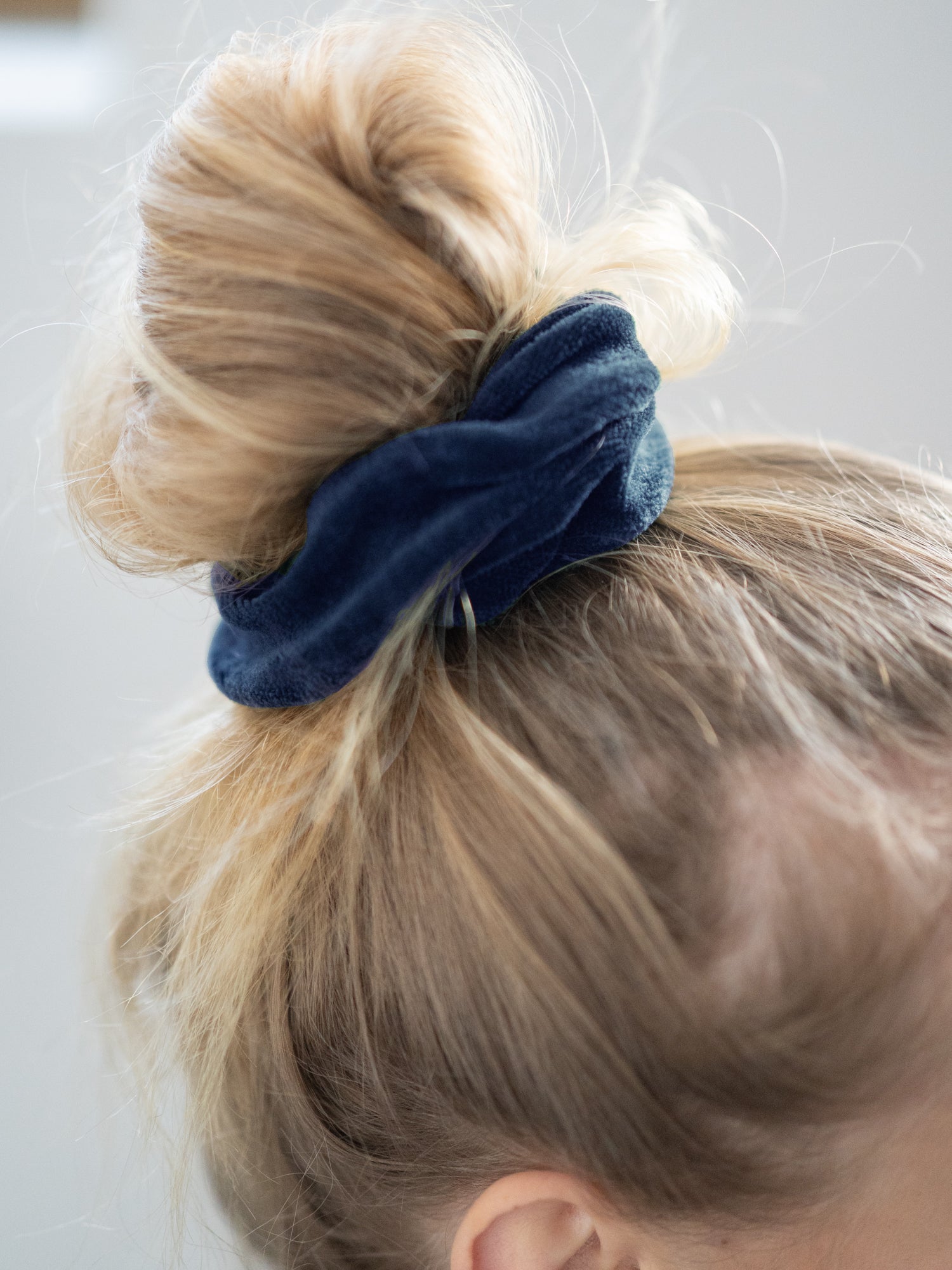 Greta trägt unser nachhaltiges und faires FUXBAU Scrunchie in navy in den Haaren als Dutt gebunden