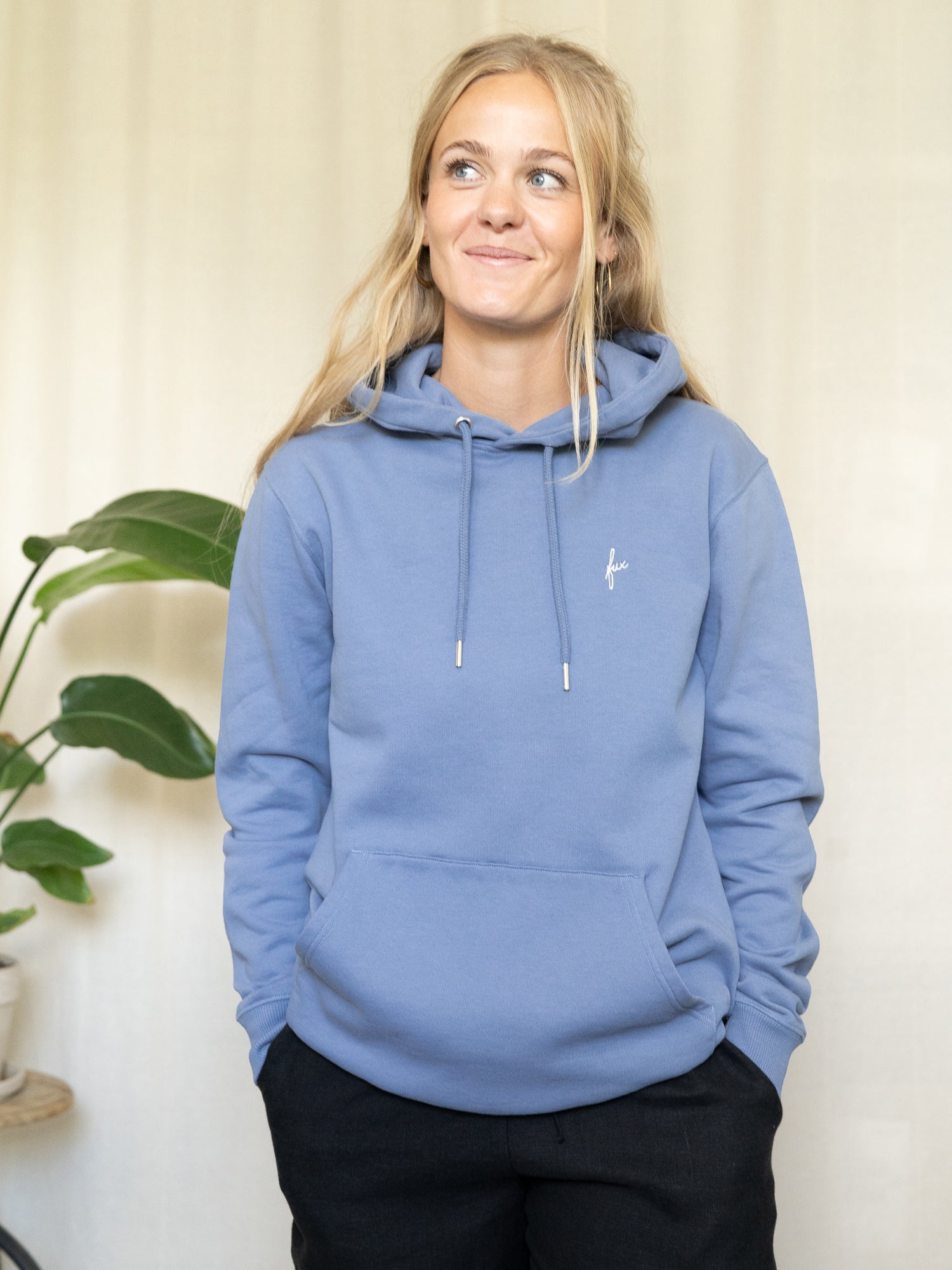 Frontalansicht des himmelblauen Hoodies mit dezenter „fux“-Stickerei, getragen von einer Frau.