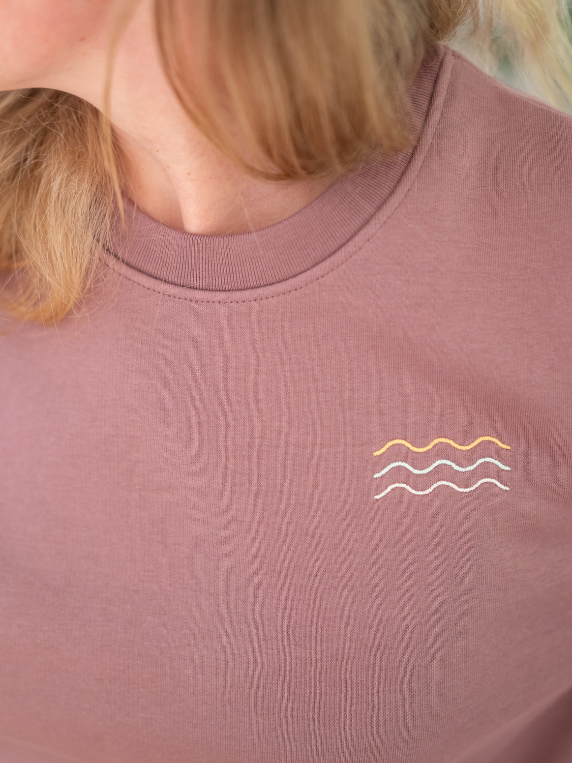 Detailansicht mehrfarbiger gestickter Wellen auf einem nachhaltigen Unisex Sweater aus Biobaumwolle in rot von FUXBAU.