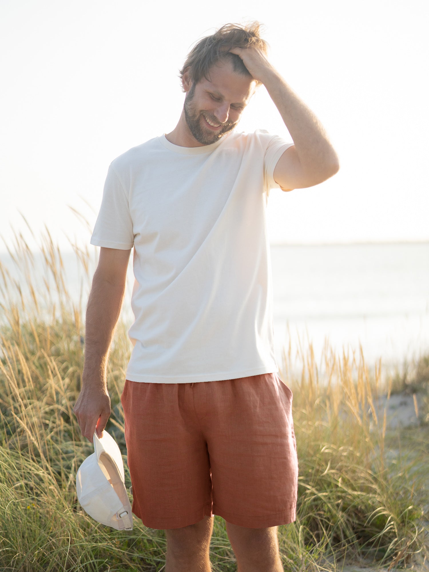 Unser Freund Philipp ist 1,94m groß und trägt die nachhaltige FUXBAU Männer Leinenshorts in sienna in der Größe XL