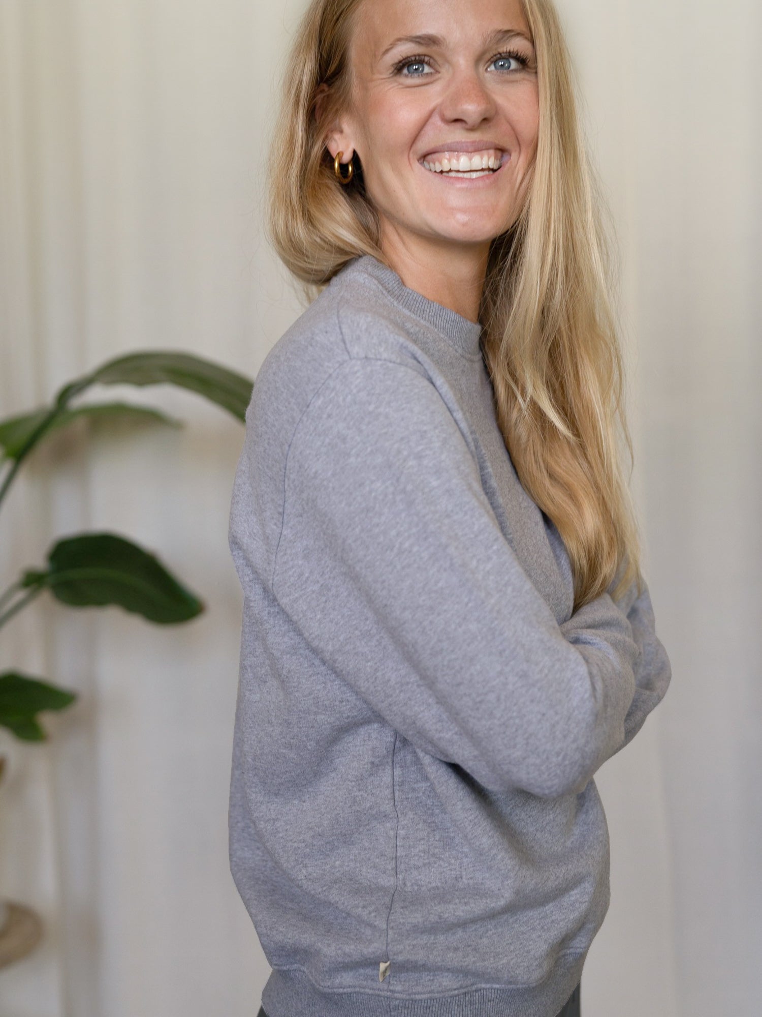 Frauen Basic Sweater graumeliert – Modell lächelt in seitlicher Ansicht, nachhaltiger Sweater aus GOTS-zertifizierter Biobaumwolle