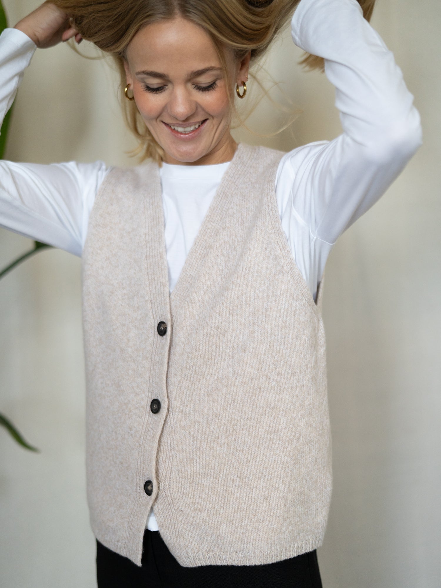 Frau trägt FUXBAU Merino Strickweste in Beigemeliert – weiche, natürliche Weste aus 100 % Merinowolle, gefertigt in Deutschland